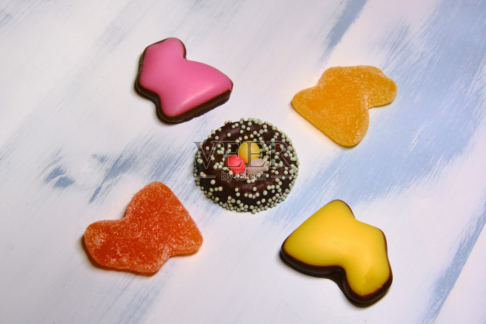 用橘子酱和巧克力蛋在白色的背景上做成兔子形状的复活节糖果照片摄影图片