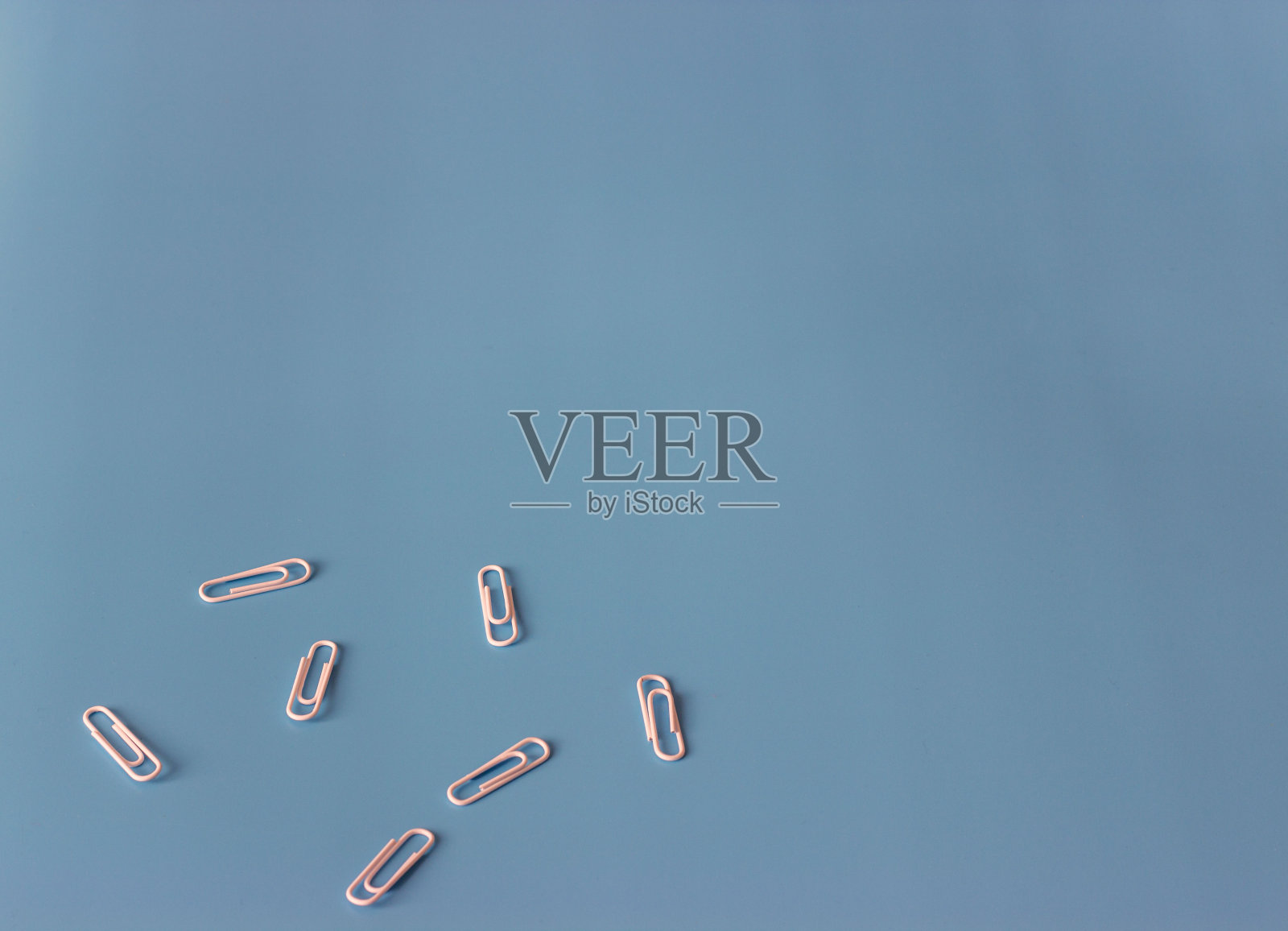 蓝色背景上的曲别针。平的。前视图。文本复制空间照片摄影图片