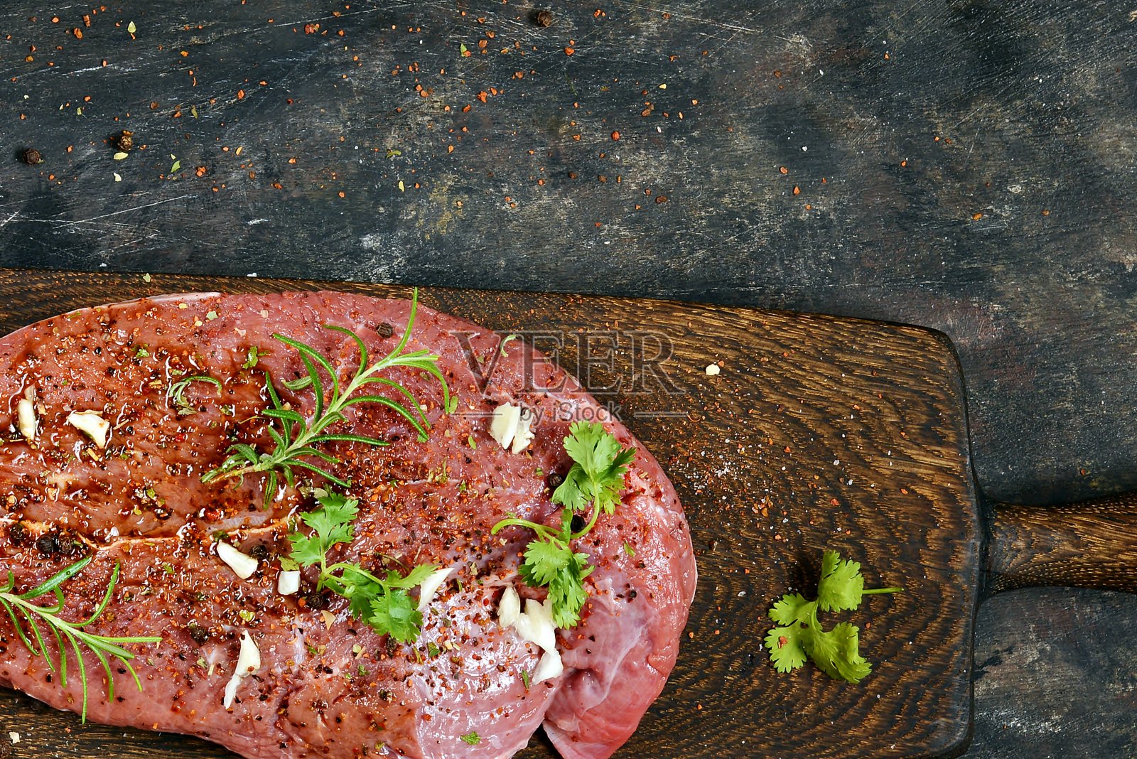 新鲜的生牛肉片与香草和香料在木板上在黑暗的背景。做饭用的一块好肉。照片摄影图片