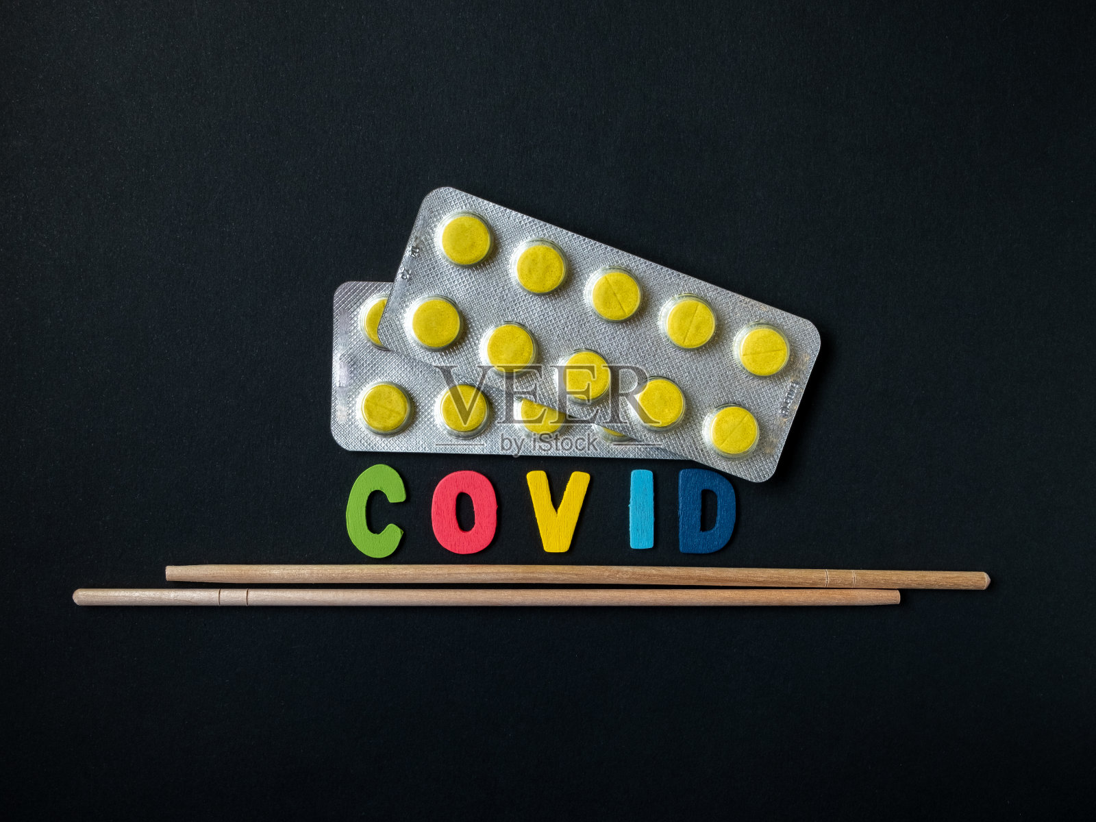 带有黄色药丸的水泡，代表病毒的题字和黑色背景上的亚洲筷子。象征来自亚洲的冠状病毒病的形式。疫情照片摄影图片