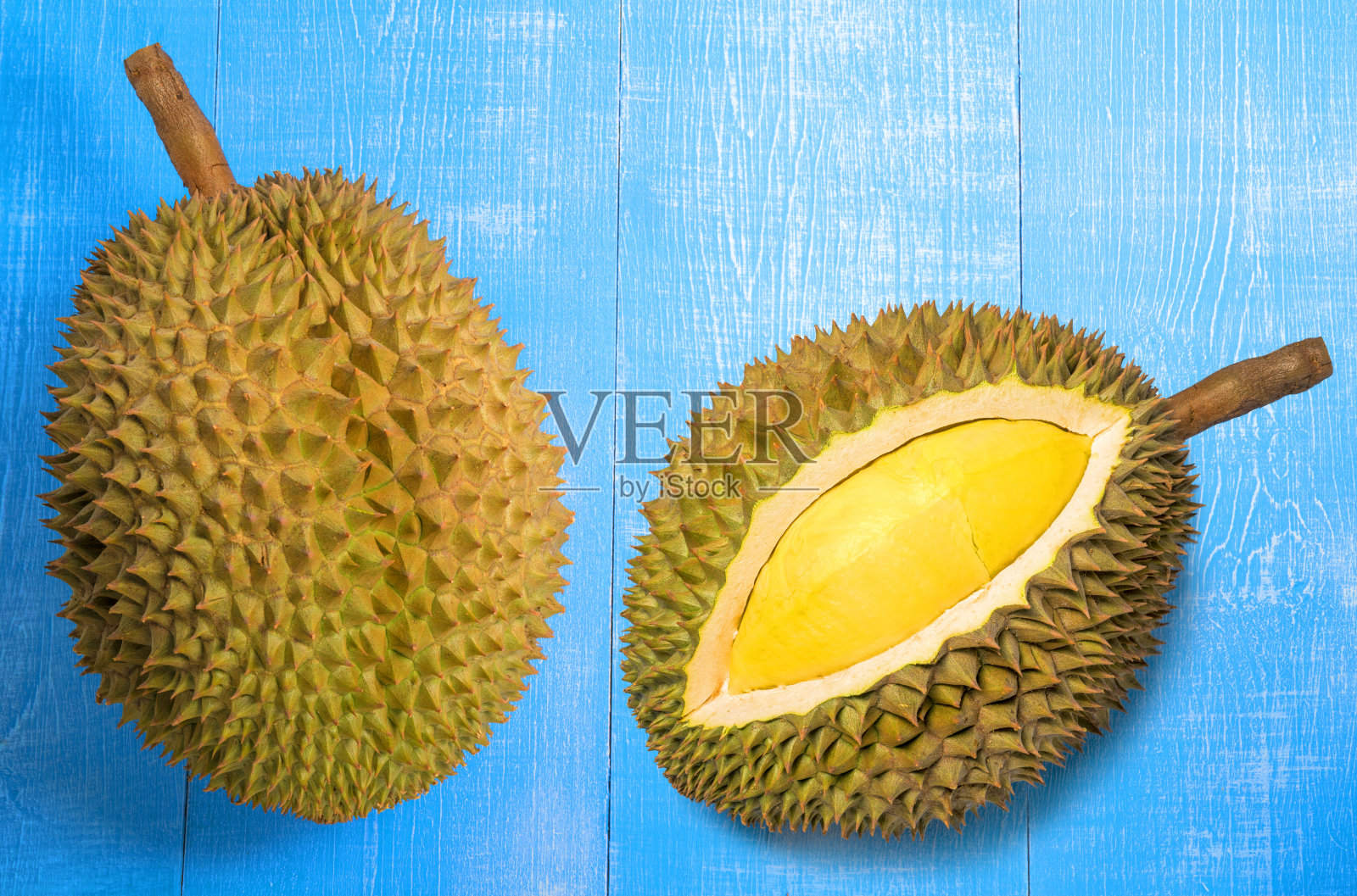 新鲜的榴莲果实在蓝色的木材背景下，榴莲果实金黄色，果肉柔软可口。照片摄影图片