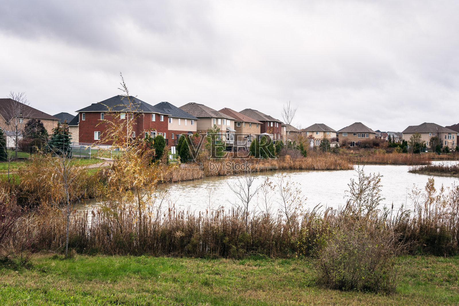 一个多云的秋日，前景中有一个池塘的住宅开发项目照片摄影图片