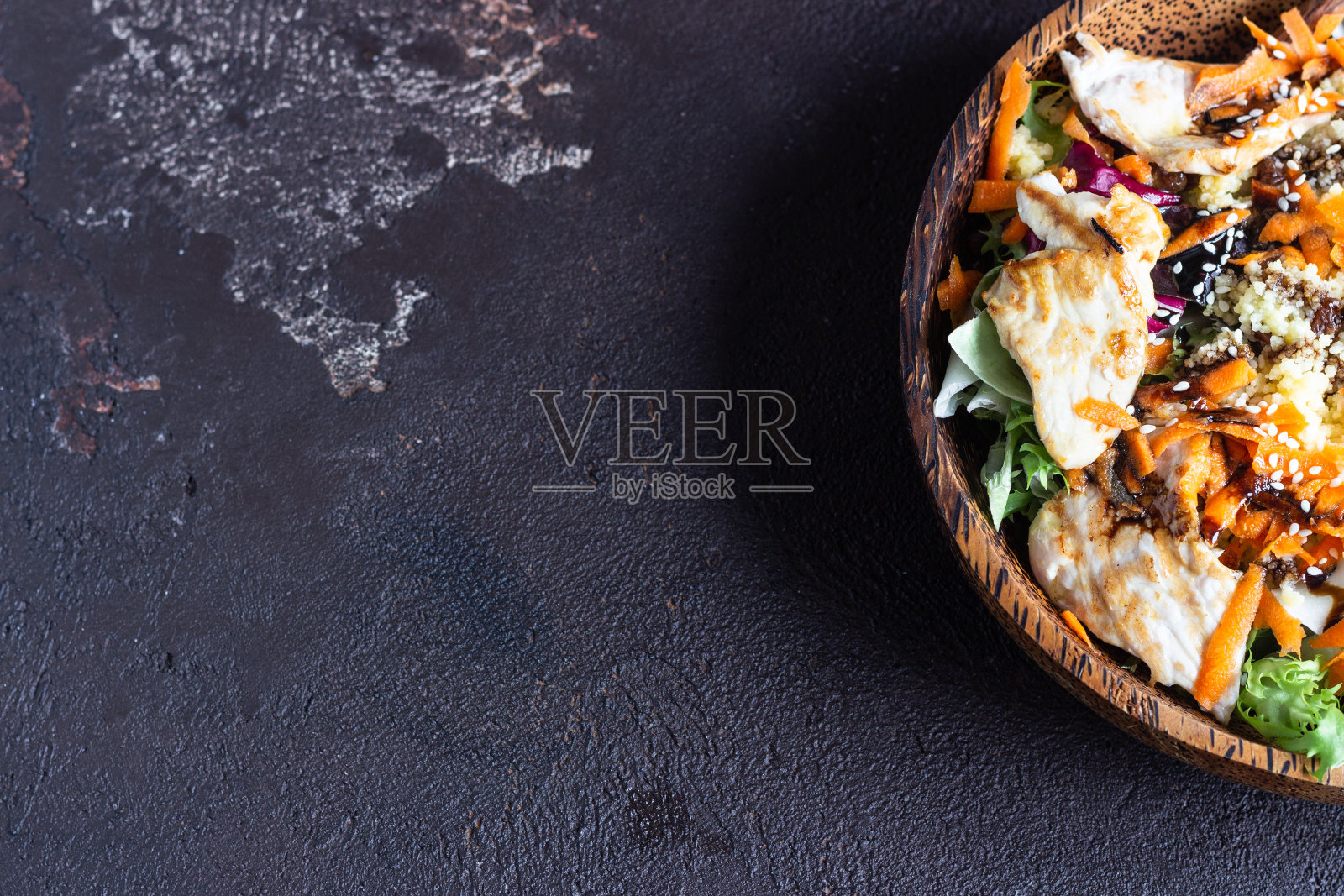 健康平衡的晚餐。佛碗午餐，配蒸粗麦粉，火鸡，胡萝卜，沙拉和芝麻。深棕色的混凝土背景。副本的空间。照片摄影图片