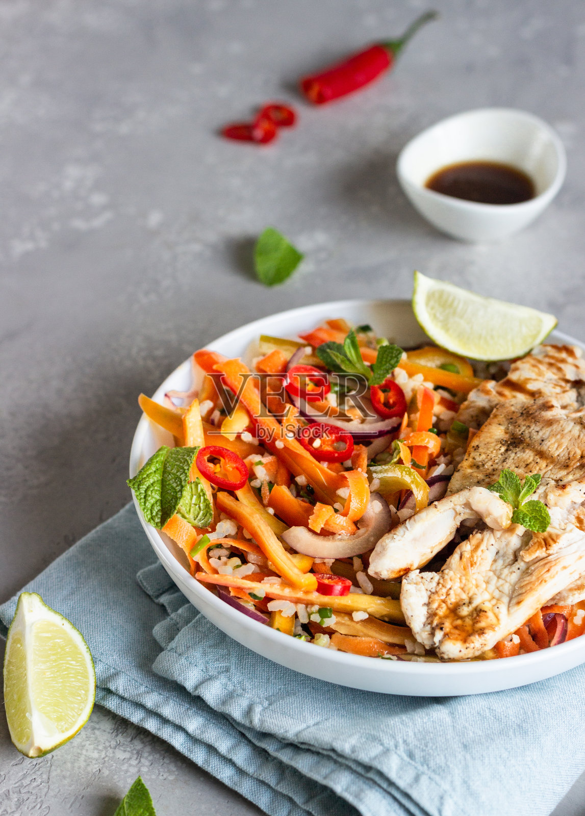 佛碗午餐配烤鸡、胡萝卜、红甜椒、洋葱、米饭和香草，以浅灰色的石头为背景。健康均衡的饮食。舒适的食物。照片摄影图片