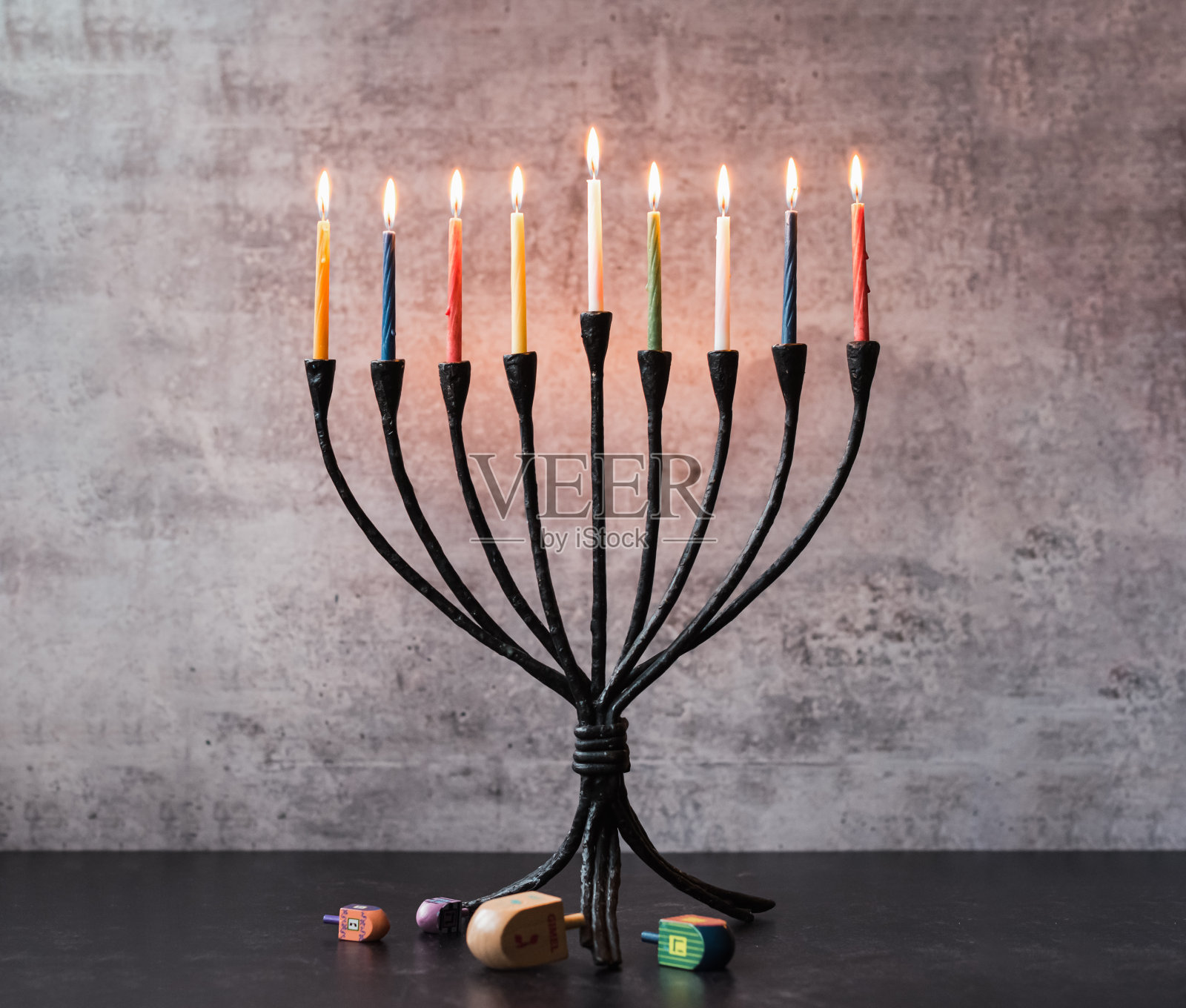 光明节的烛台上点着蜡烛，黑色的桌子上放着陀螺。照片摄影图片