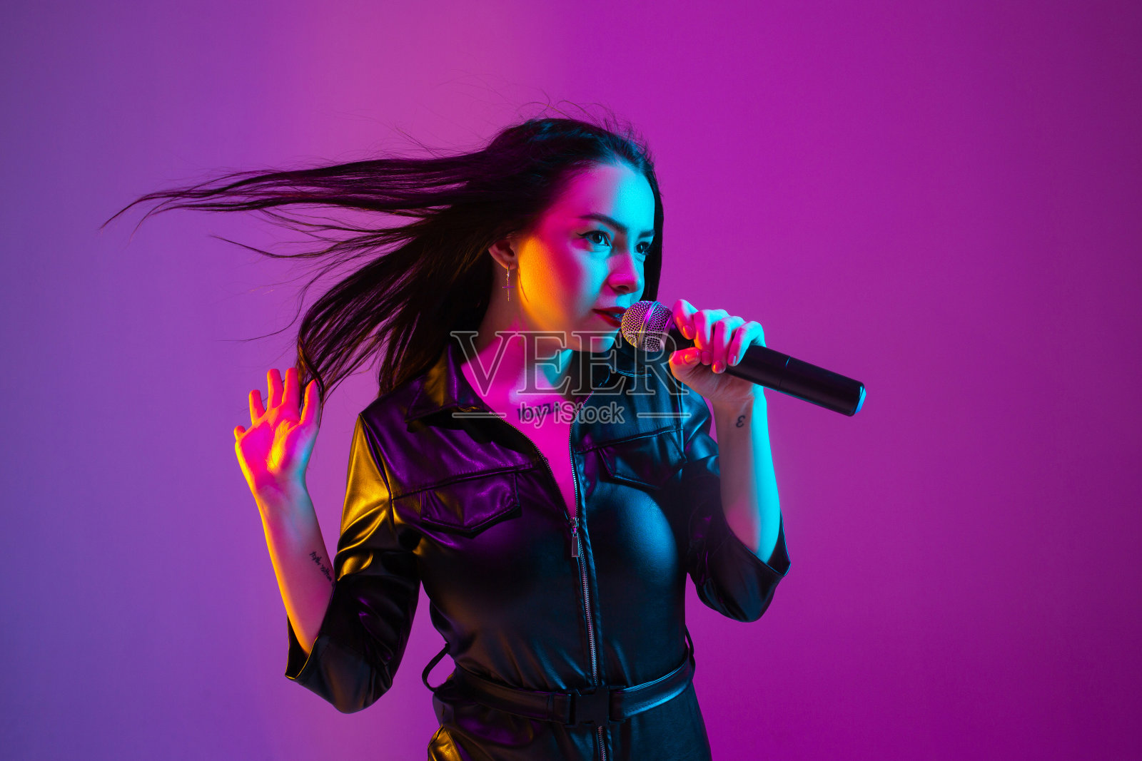 在紫色演播室霓虹灯背景下拍摄的白人女歌手肖像照片摄影图片