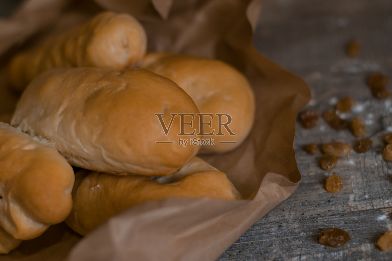 鲜红的自制糕点，牛皮纸上，葡萄干，放在一张木桌上，下面铺着棕色毛巾。照片摄影图片