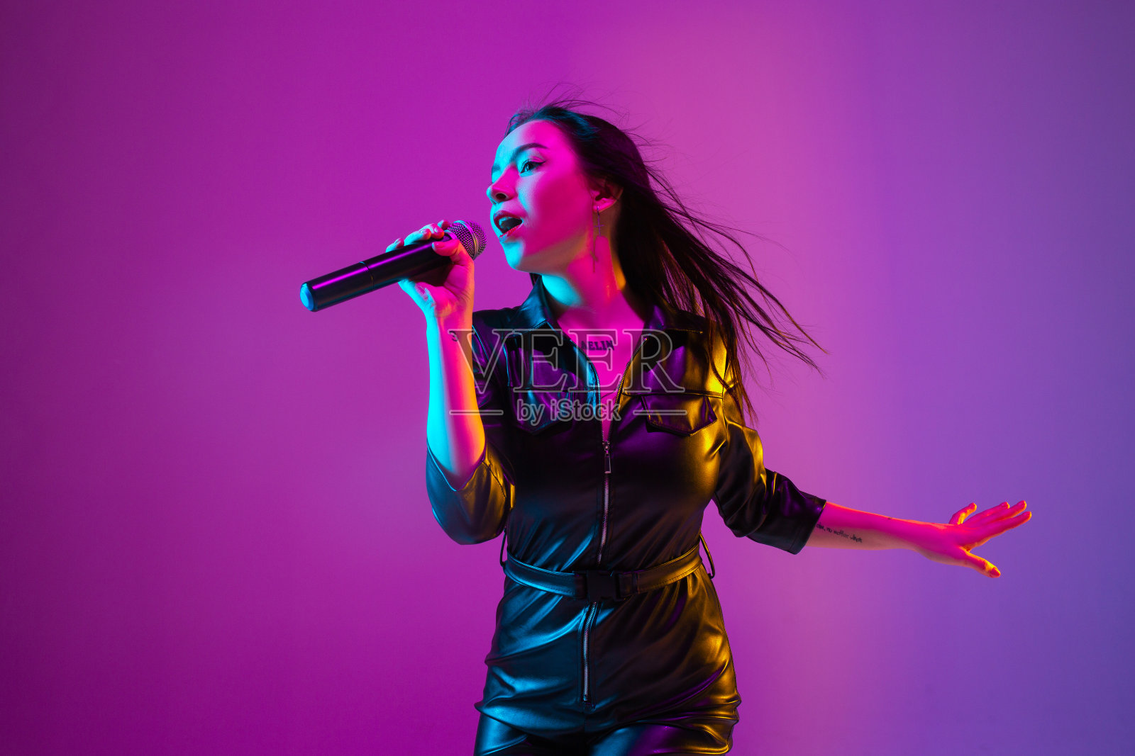 在紫色演播室霓虹灯背景下拍摄的白人女歌手肖像照片摄影图片
