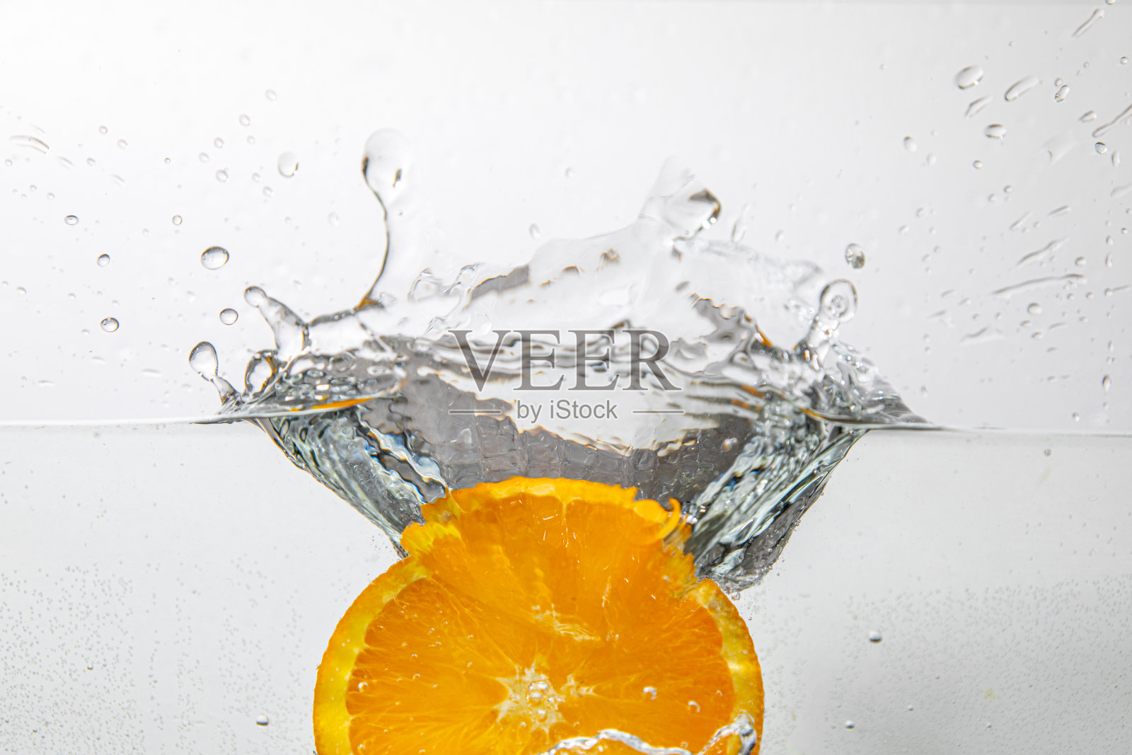 橙色薄片从上方落入水中，溅起水花照片摄影图片