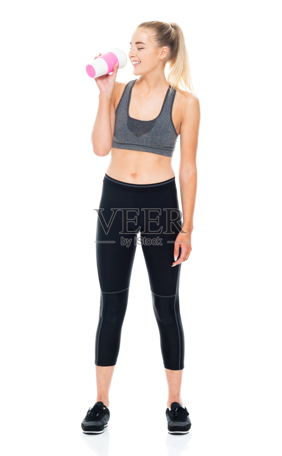 z一代的少女们穿着紧身裤，拿着咖啡杯站在白色背景前照片摄影图片