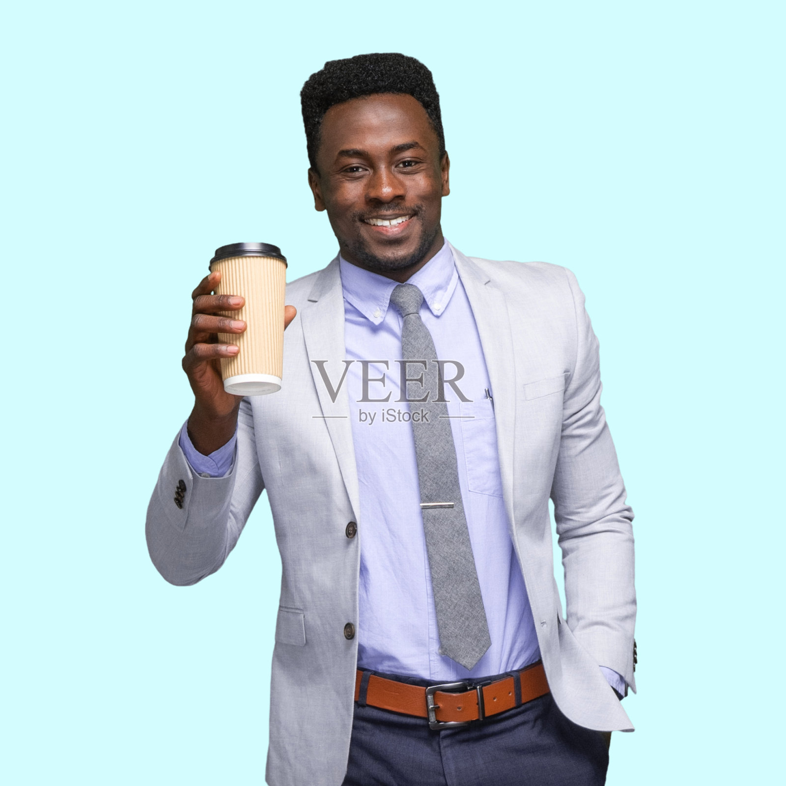 非裔美籍男性商人站在有色背景前，穿着时髦的休闲装，拿着咖啡杯照片摄影图片