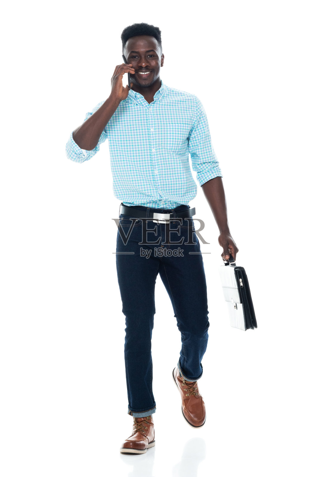 z一代男性走在白色背景前，穿着有纽扣的衬衫，拿着公文包，使用手机照片摄影图片