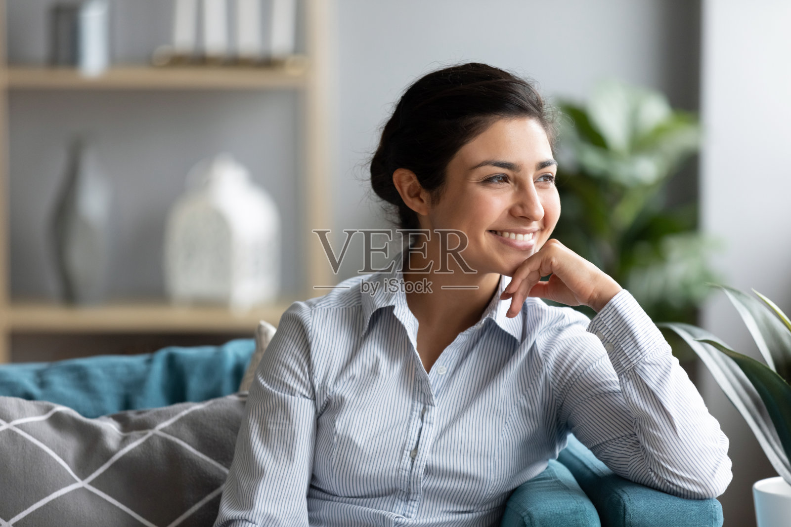 微笑的少数民族女孩坐在沙发上陷入沉思照片摄影图片