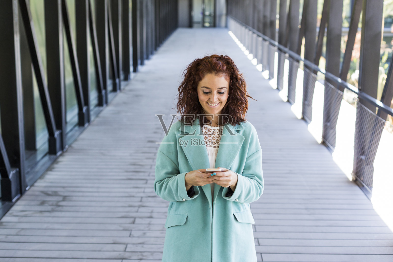 年轻漂亮女人面带微笑，使用手机，室内照片摄影图片