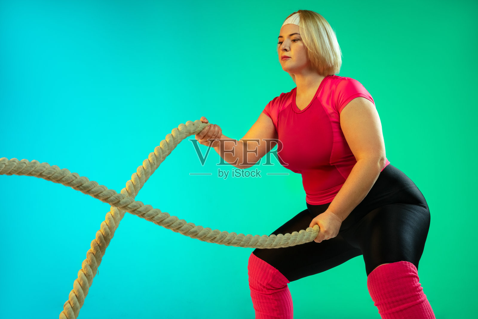 在渐变绿色背景下训练的年轻白人加大码女模特照片摄影图片