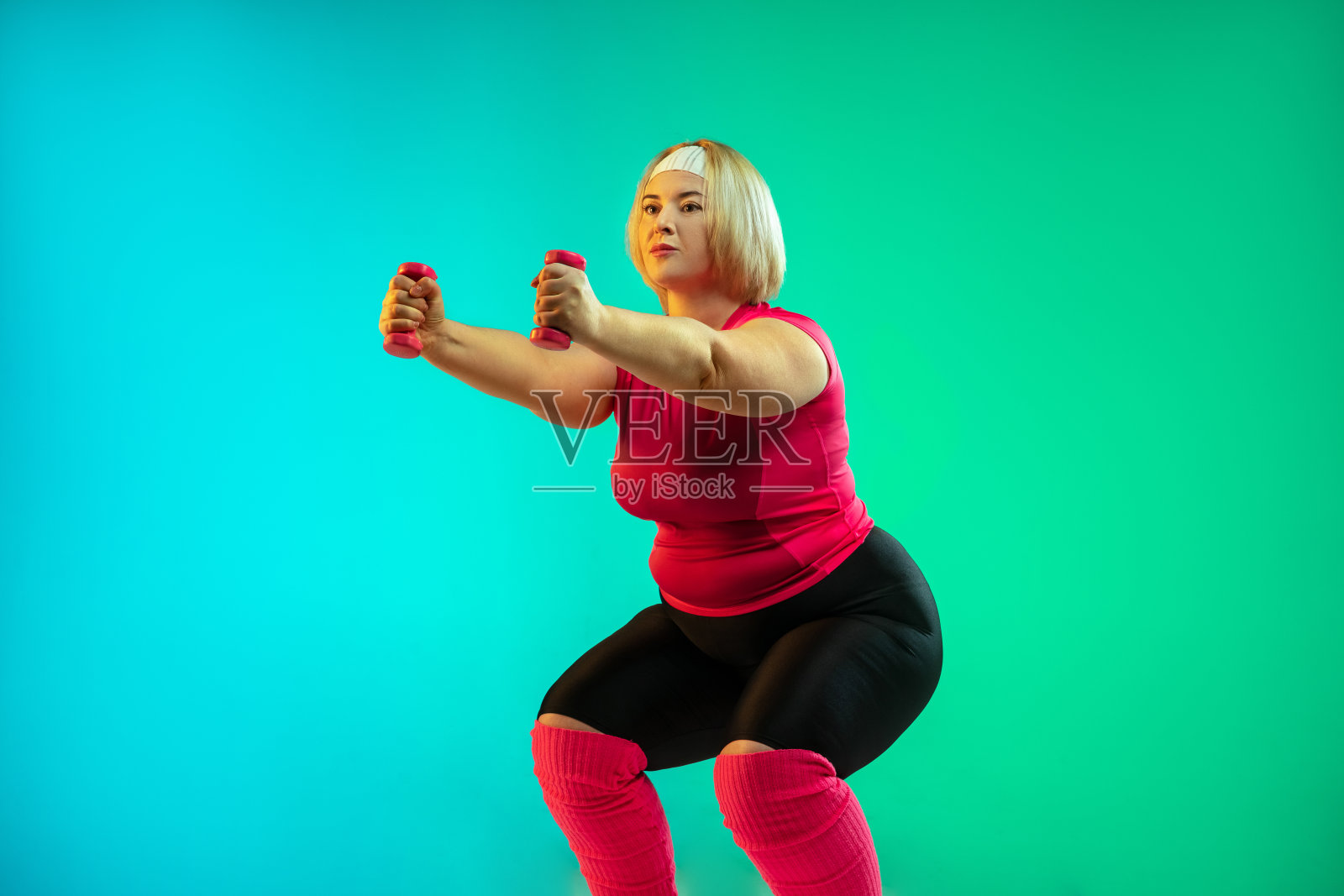 在渐变绿色背景下训练的年轻白人加大码女模特照片摄影图片