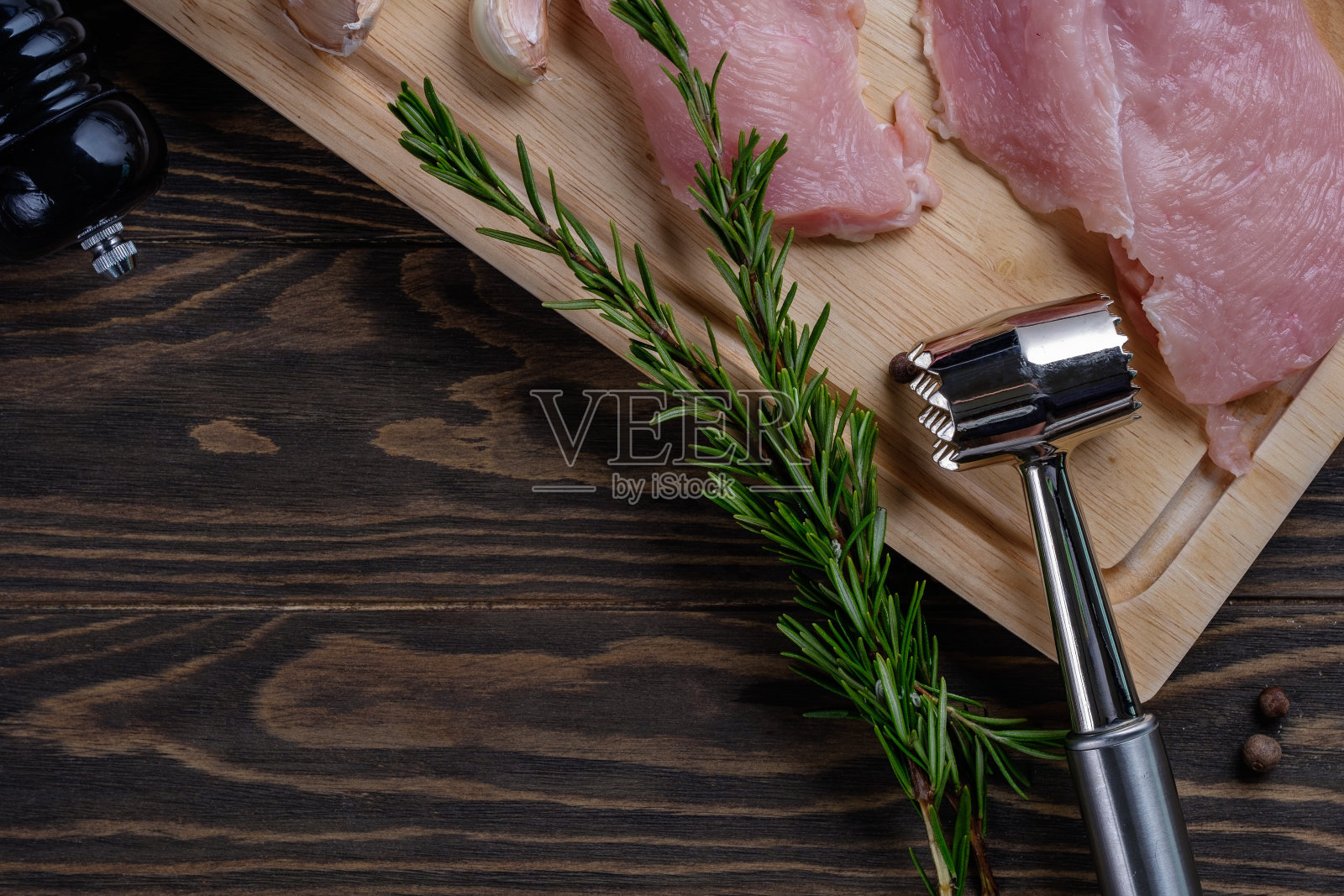 木板上放着新鲜的生鸡胸肉，木桌上放着香料和香草照片摄影图片