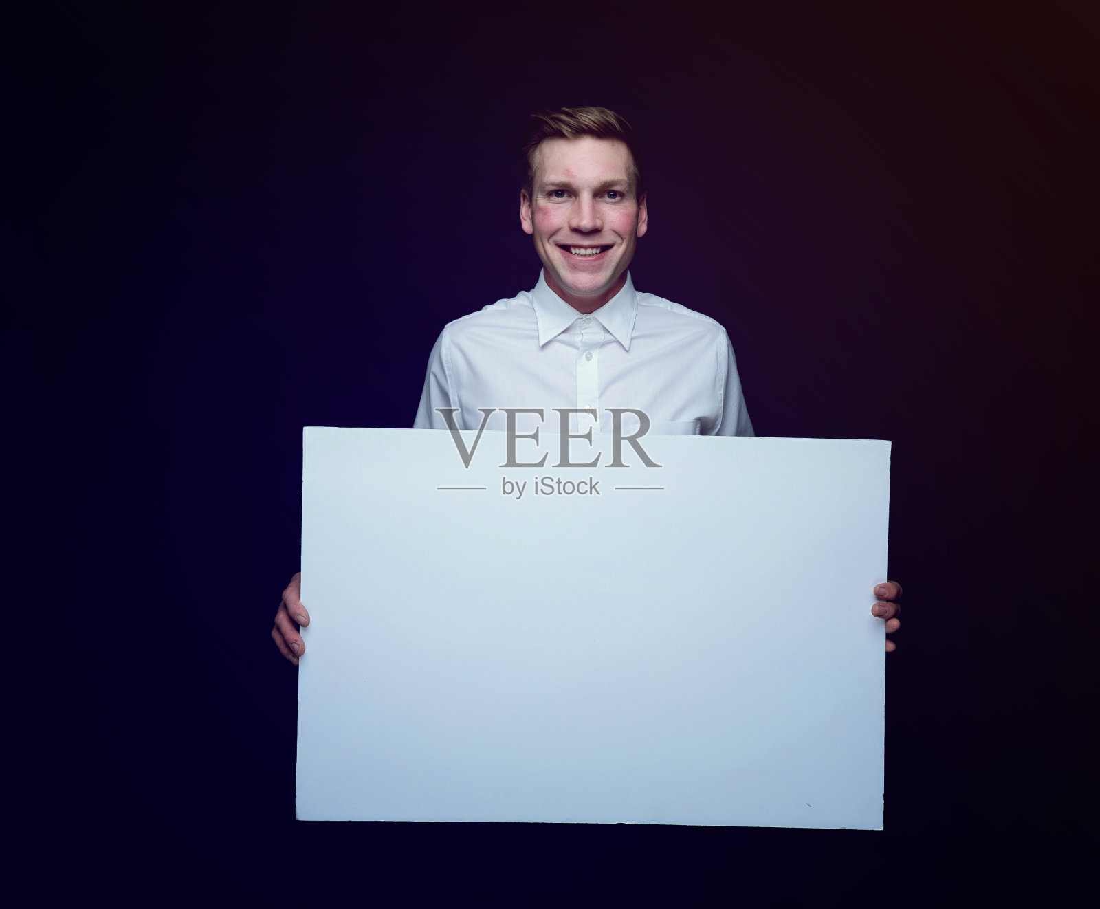 白人年轻男性在前面的紫色背景穿着纽扣衬衫和举着告示照片摄影图片