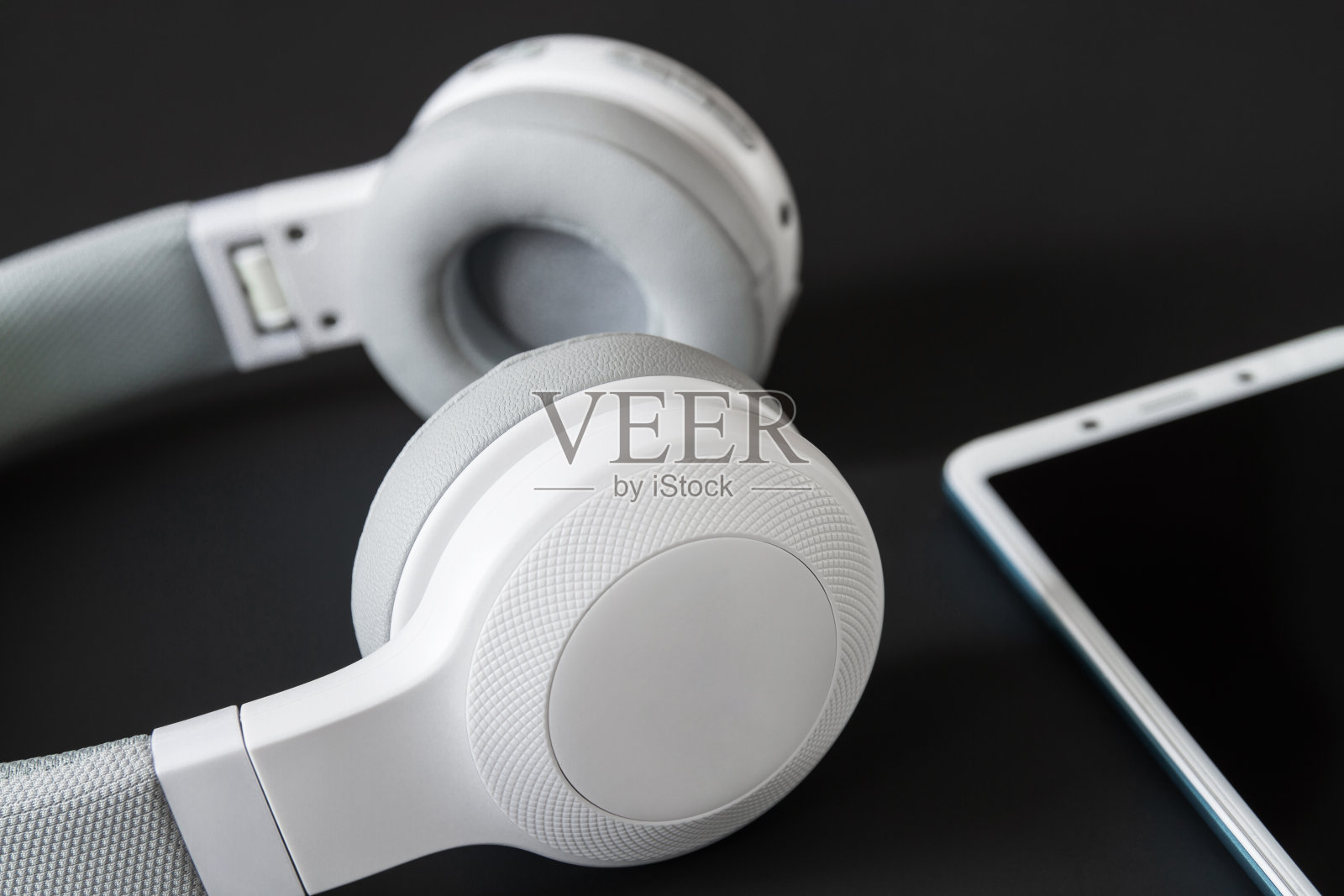 黑暗背景下的无线耳机和智能手机。特写镜头,有选择性的重点照片摄影图片