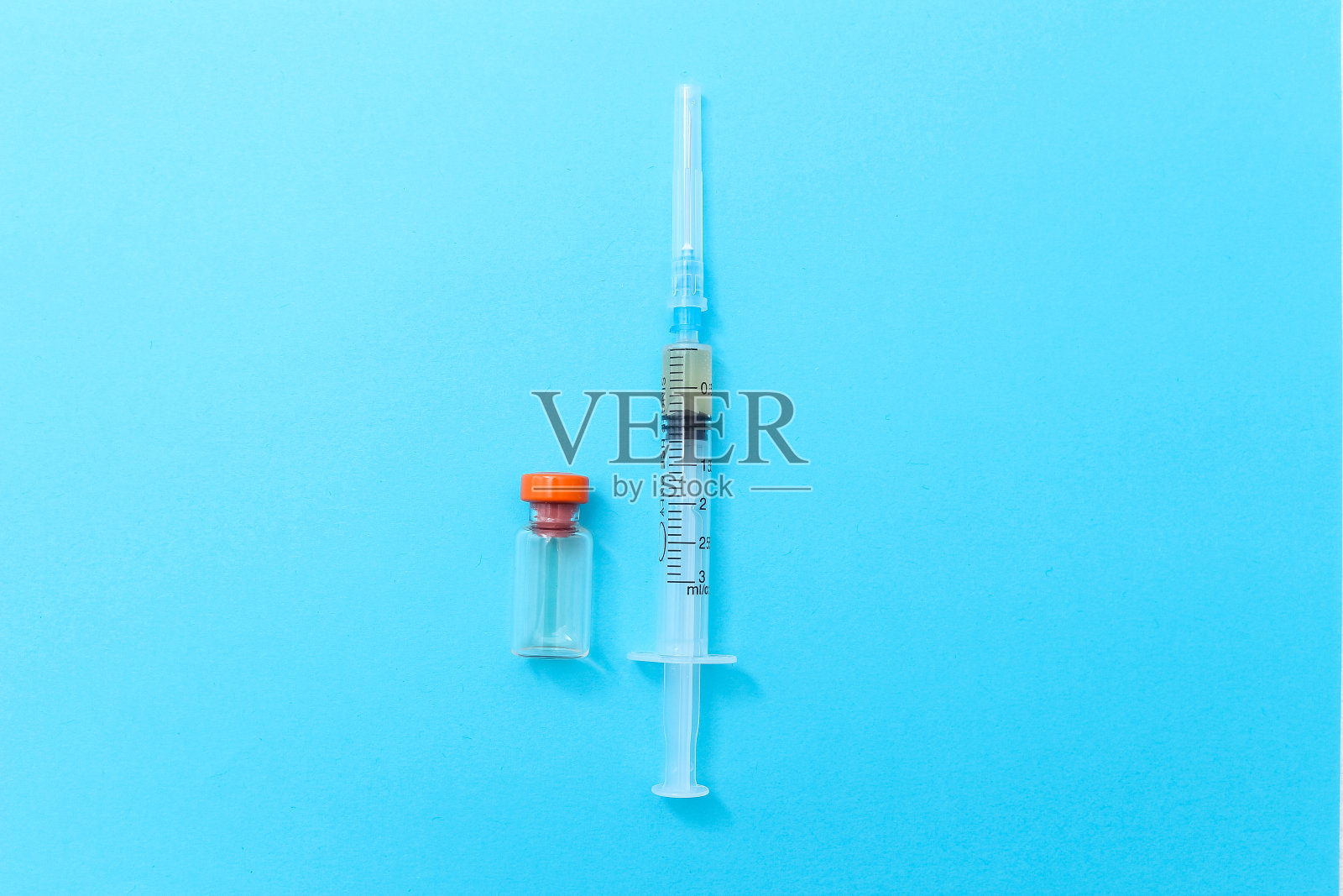 蓝色背景上的一次性注射器和药瓶。接种疫苗，流感季节医学概念照片摄影图片