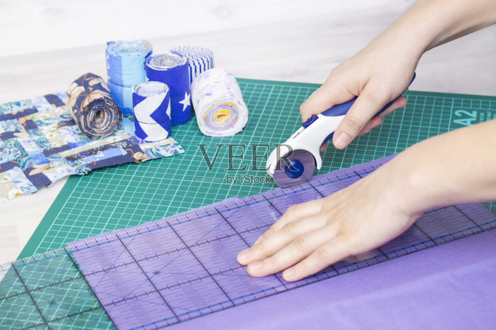 棉被的碎片，用于拼接的配件。女裁缝用手剪开做被子的布料。拼布垫，尺，刀垫照片摄影图片