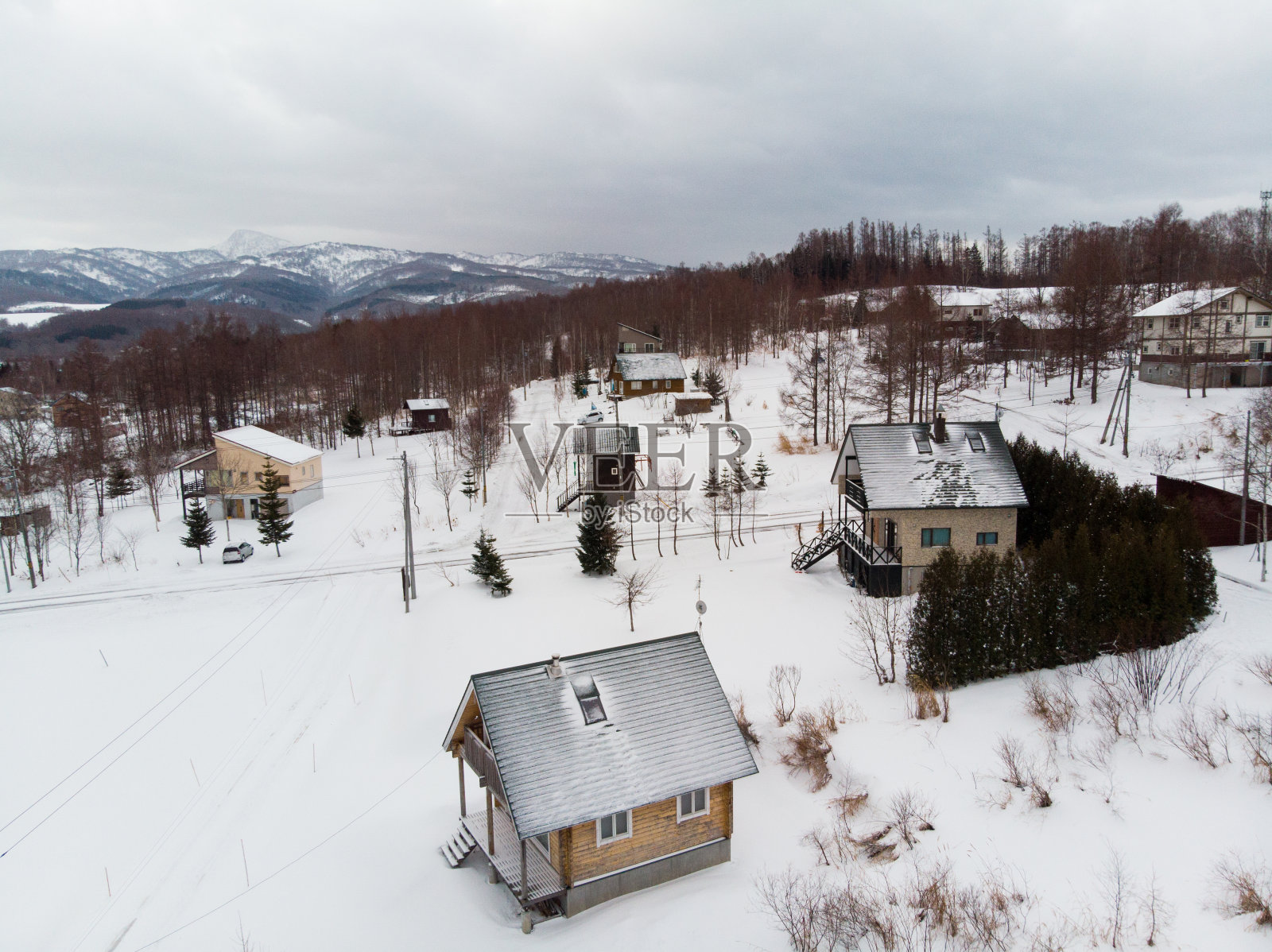 冬天的风景照片，雪覆盖的田野和村舍与光秃秃的树木在前景和雄伟的Yotei山在背景照片摄影图片