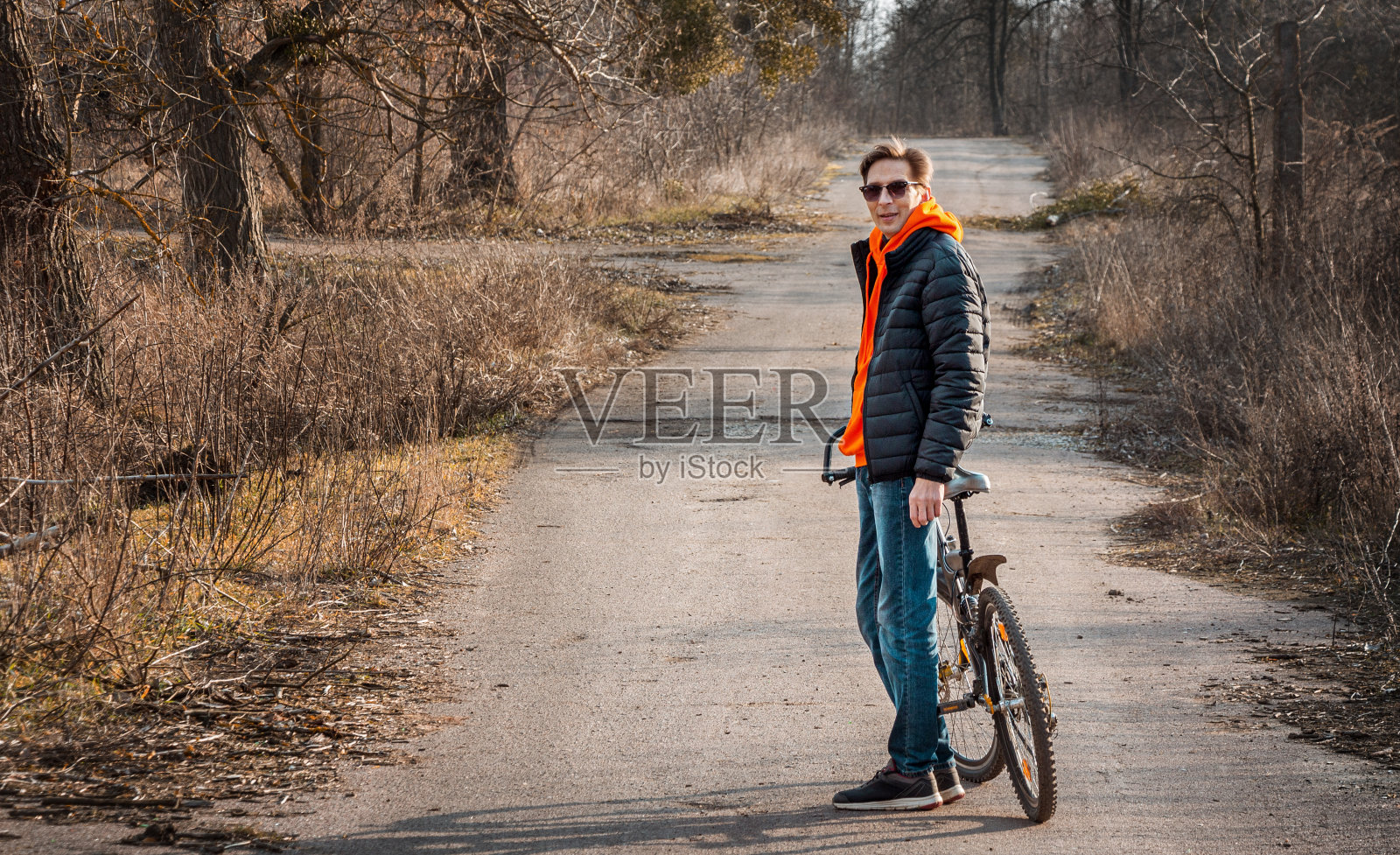 戴眼镜的男子在沥青路上手推自行车照片摄影图片