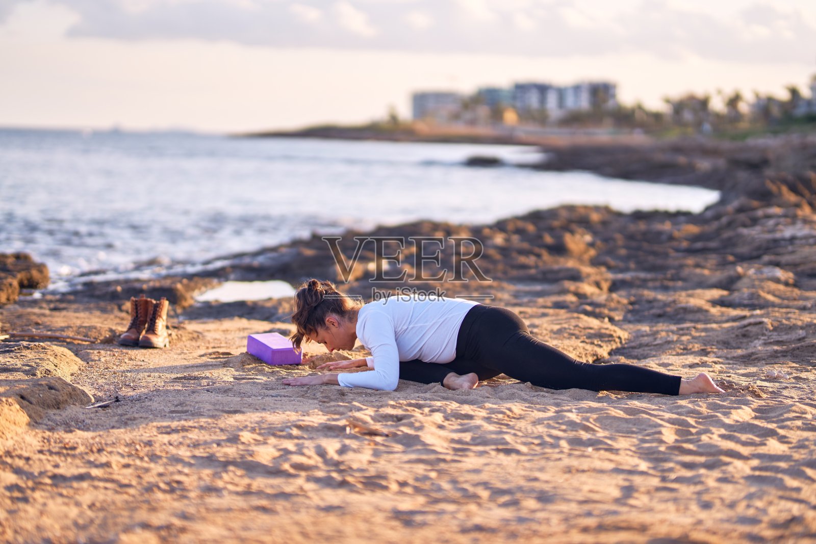 年轻漂亮的运动女人练习瑜伽，教练在海滩伸展照片摄影图片