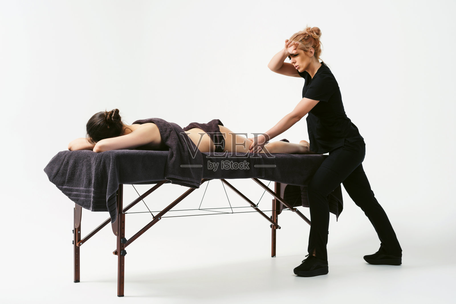 趣味燃脂按摩。快乐女按摩师在康复中心按摩台旁为女顾客按摩，白色背景隔离照片摄影图片