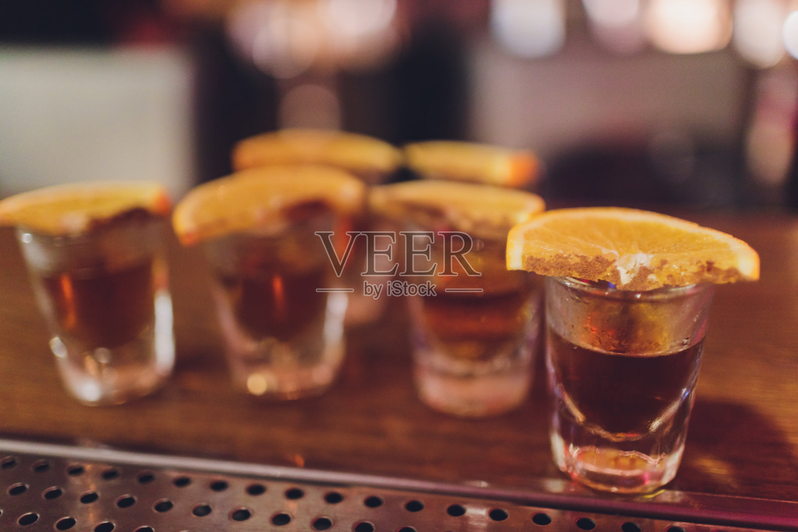 干蜜饯橙，酸橙和柠檬轮在大的玻璃容器中，内容物也安排在屠夫块周围的罐子与生糖和金属盖。照片摄影图片