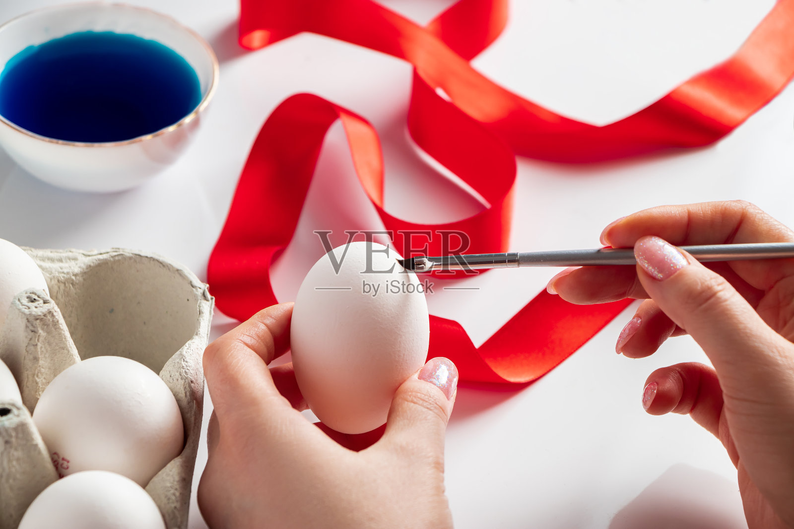 年轻女子为复活节画白色的蛋。照片摄影图片