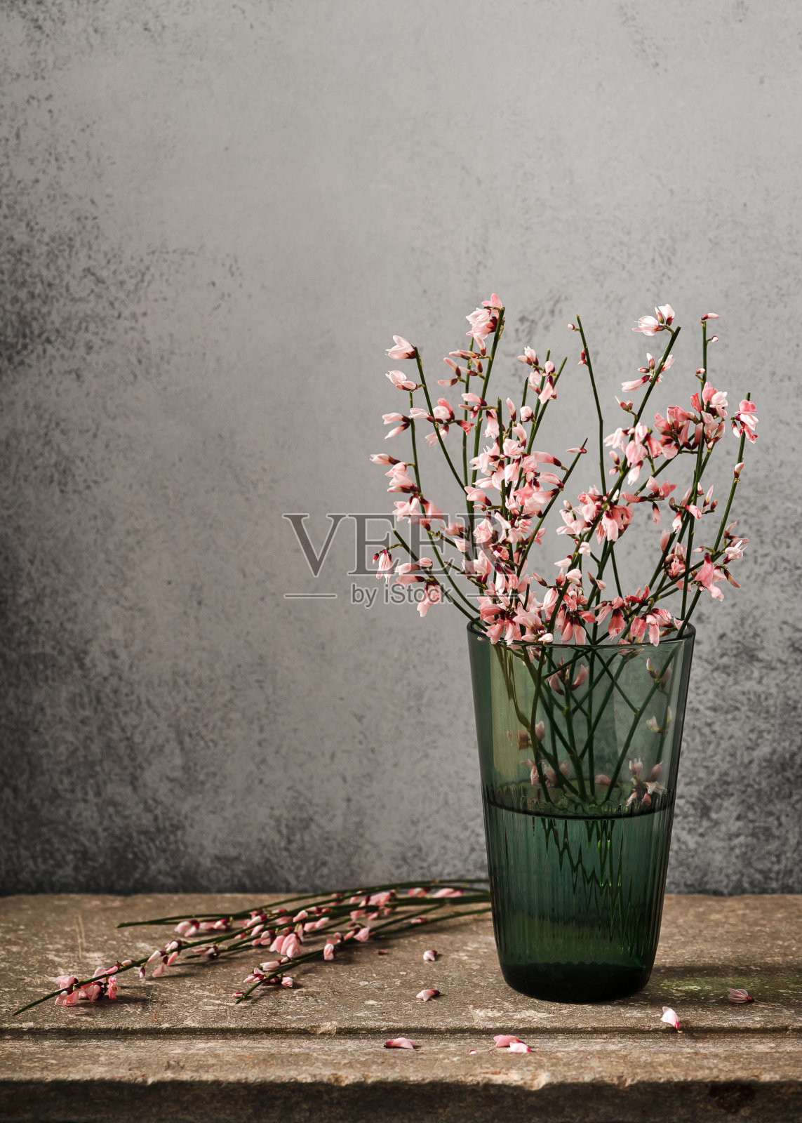 静物与一束盛开的粉红色金龟子花在绿色玻璃花瓶。照片摄影图片