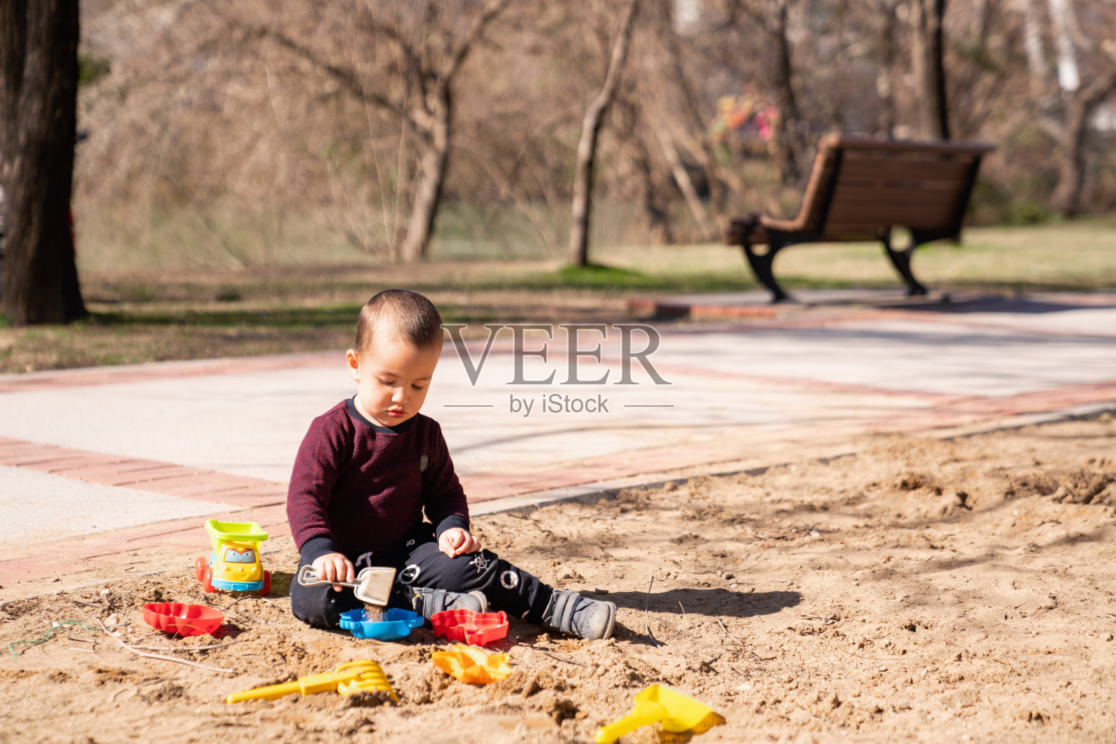 可爱的小男孩在沙盒里玩塑料玩具。概念游戏在户外在春天或夏天的时间。照片摄影图片