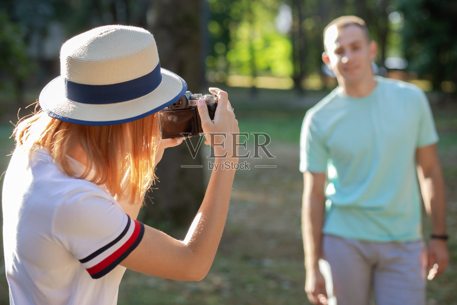 年轻情侣在阳光明媚的夏日公园里互相拍照照片摄影图片