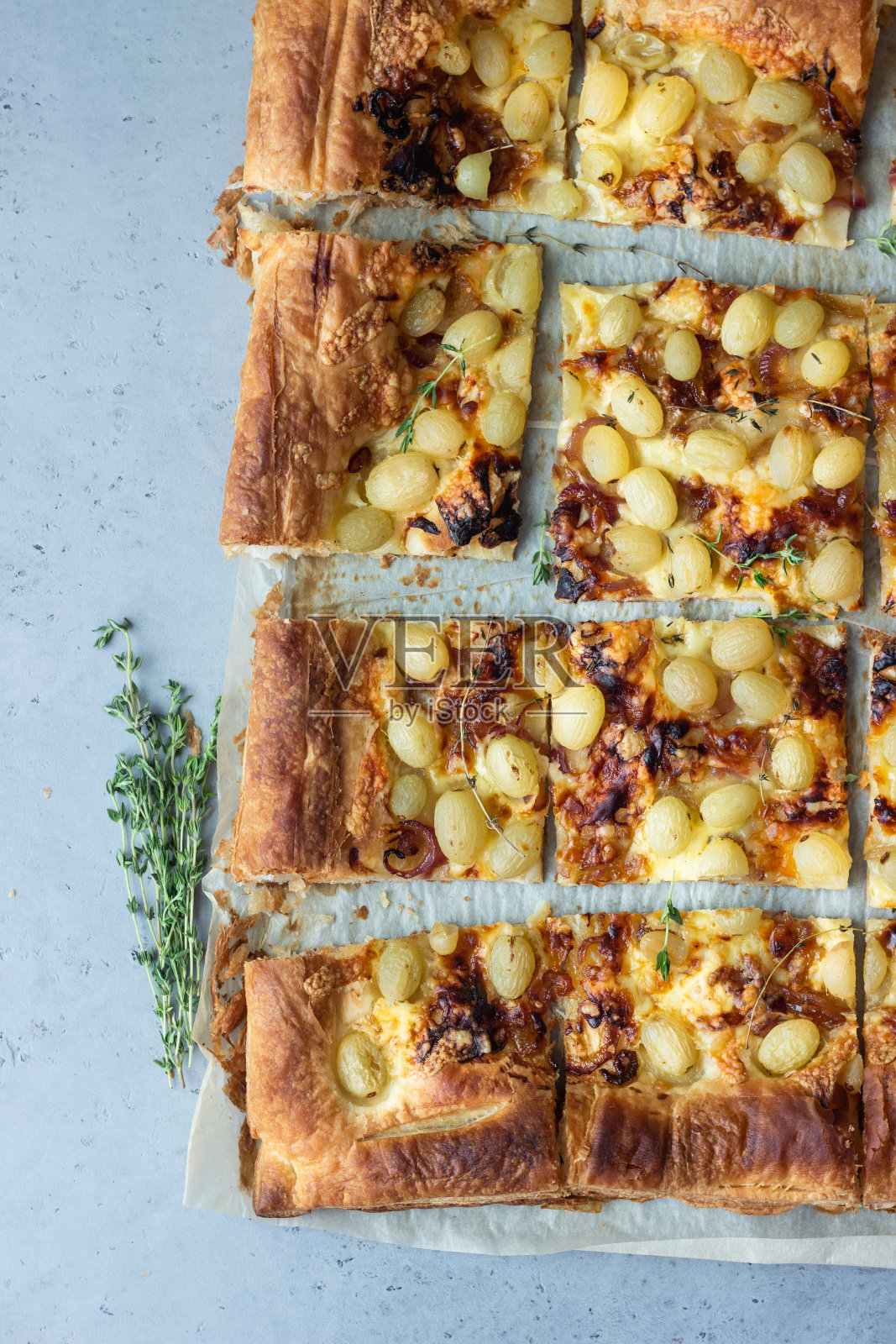 由酥皮、焦糖洋葱、奶酪、百里香和绿葡萄制成的美味馅饼。与葡萄面包。照片摄影图片