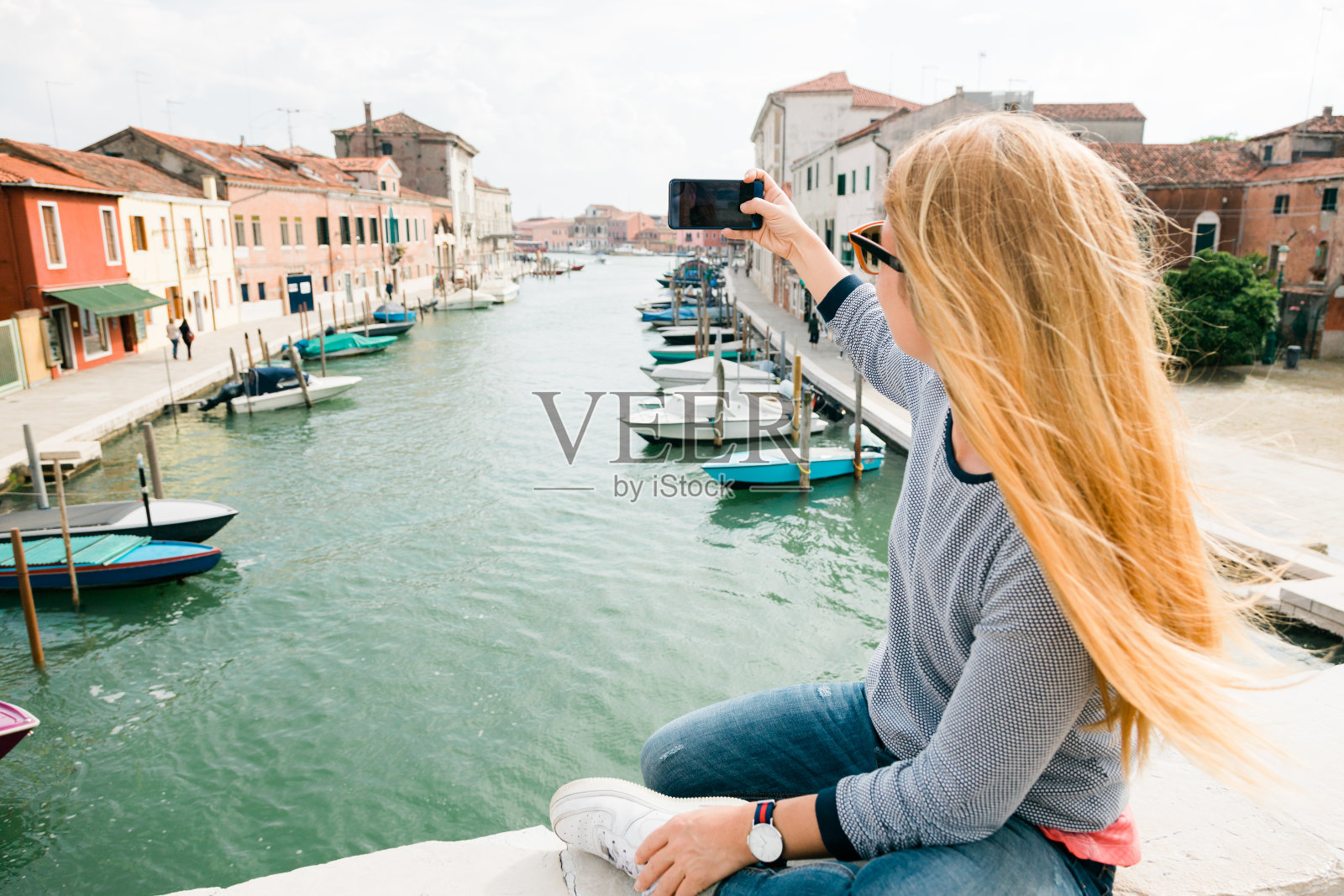 年轻女人在意大利威尼斯穆拉诺桥上打电话照片摄影图片