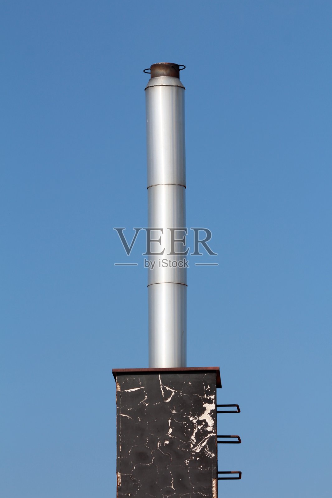 闪闪发光的金属工业烟囱，上面涂着黑色裂缝漆的混凝土地基照片摄影图片