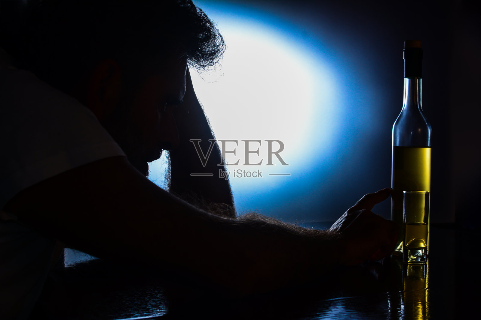 坐在桌旁触摸酒瓶的男人剪影照片摄影图片