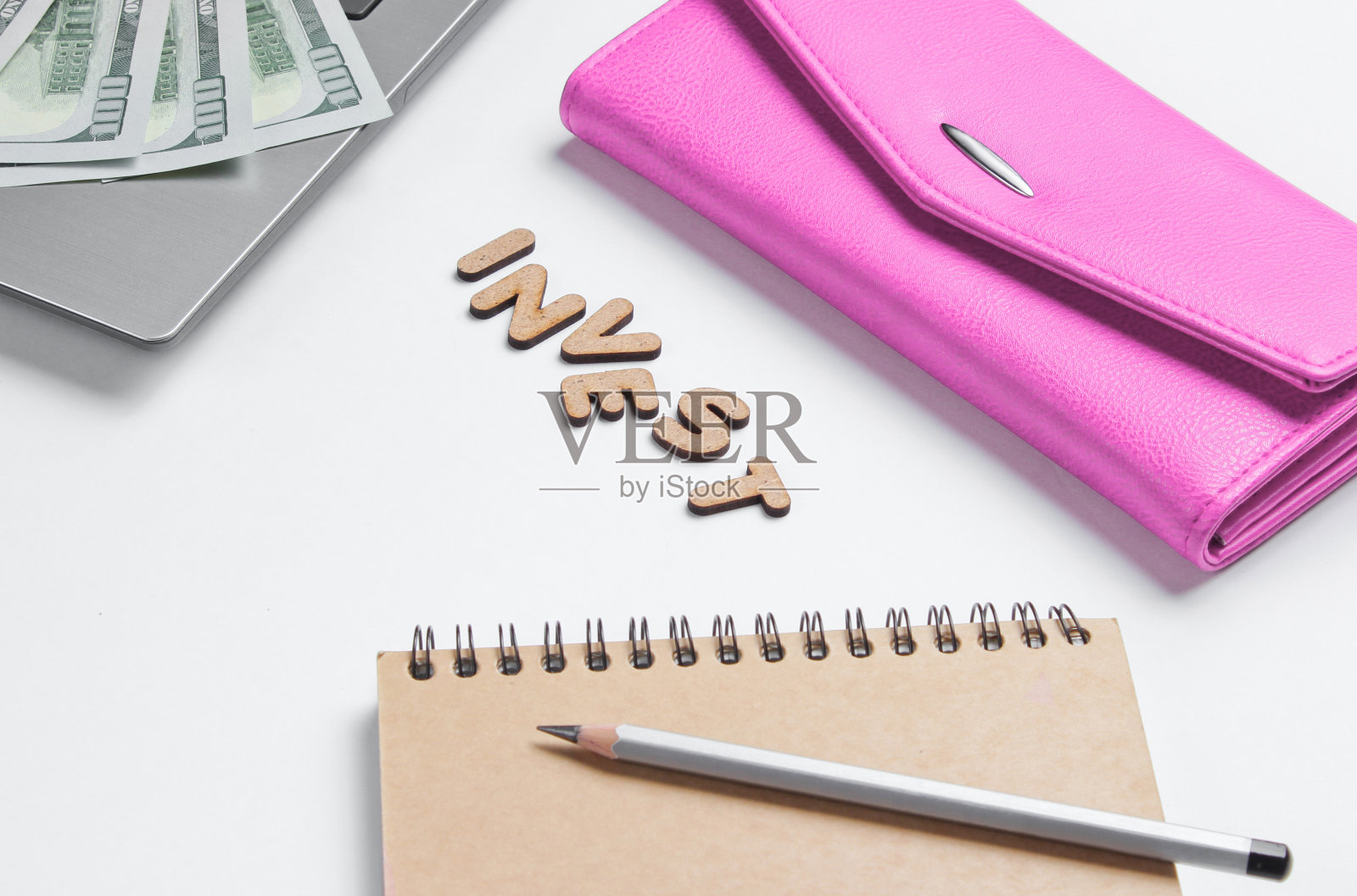 创造性的经营理念。笔记本、笔记本、铅笔、钱包，白色背景上印有印有木制字母的投资字，极简主义照片摄影图片