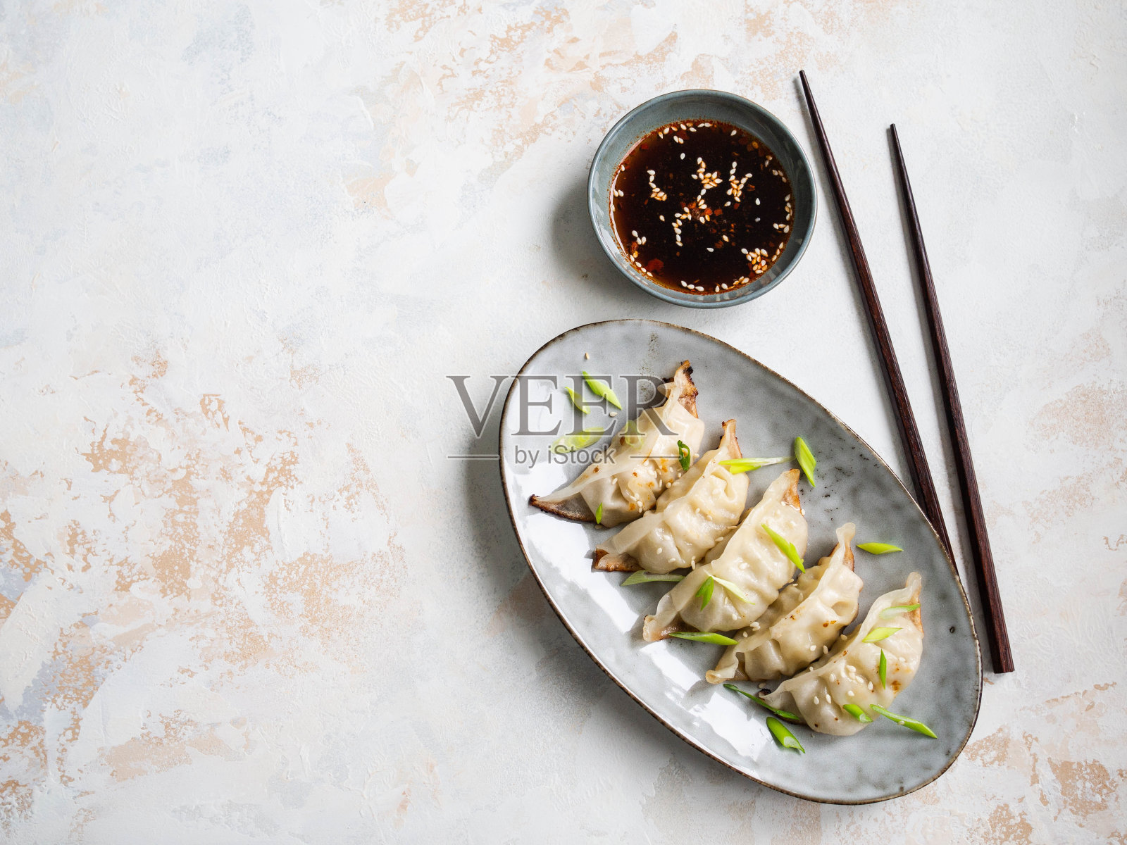 中国传统的饺子——在一个椭圆形的盘子里放着猪肉和蔬菜，碗里放着酱油。照片摄影图片