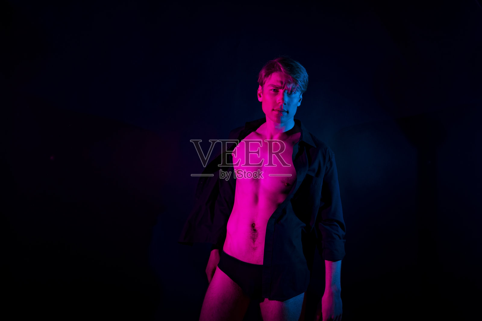 彩色背景前穿泳裤的年轻白人男子照片摄影图片