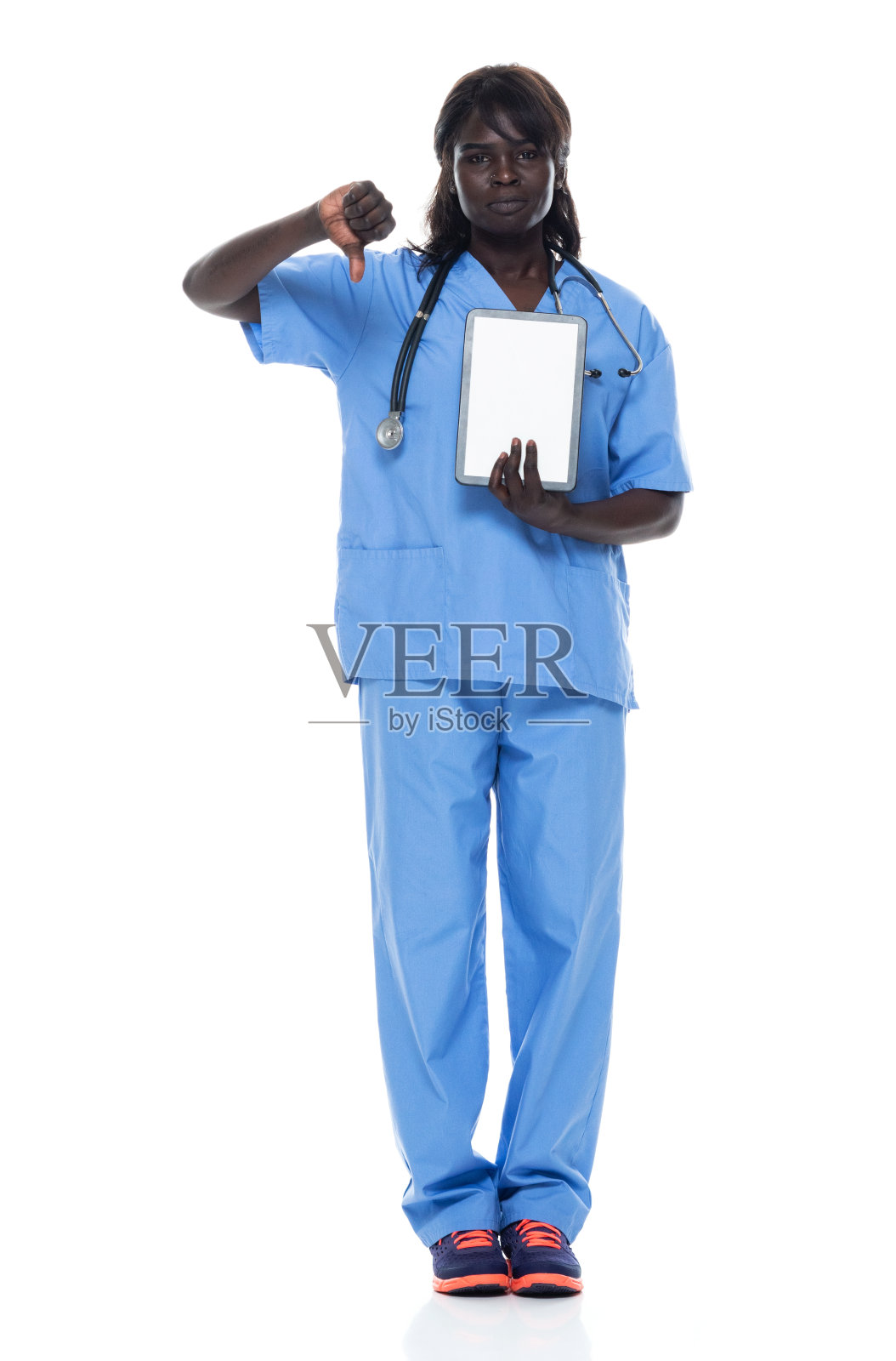 非洲裔年轻女性穿着运动鞋，使用数码平板电脑站在白色背景前照片摄影图片