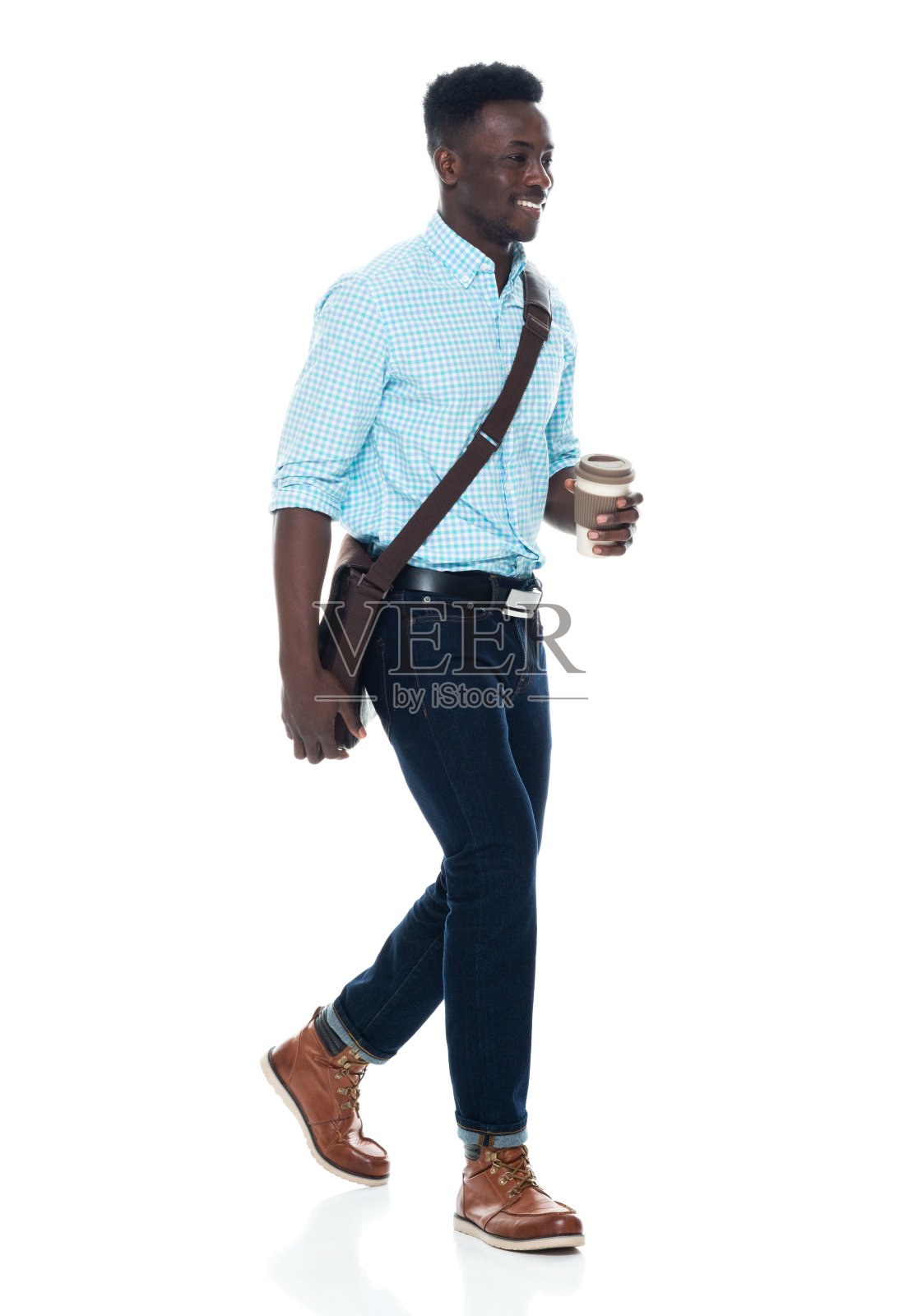 非裔美国男性，肩包，手拿咖啡杯，走在白人背景前照片摄影图片