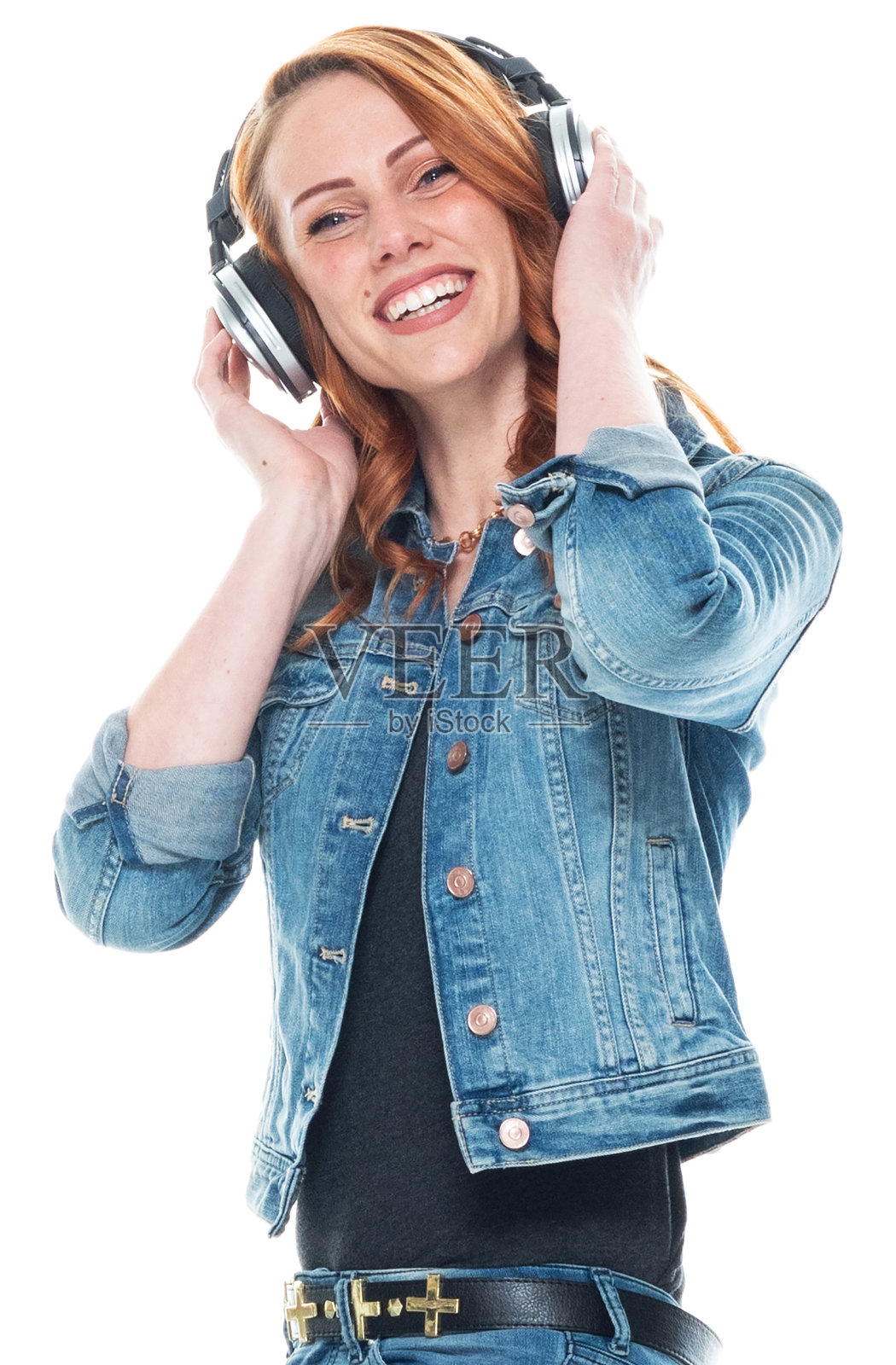 白人年轻女性穿着裤子戴着耳机站在白色背景前照片摄影图片