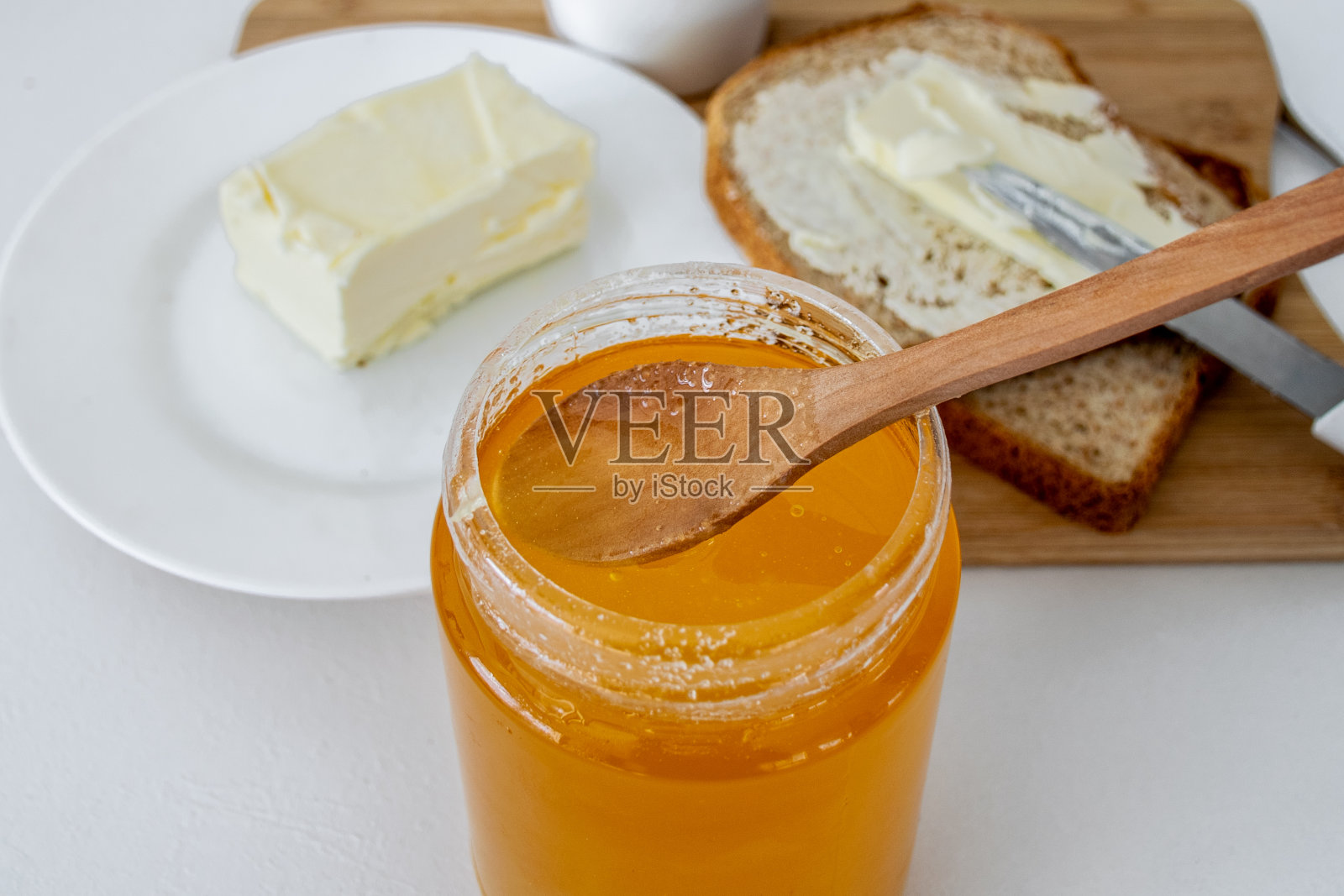 白色的桌子上放着蜂蜜，法式吐司和黄油照片摄影图片