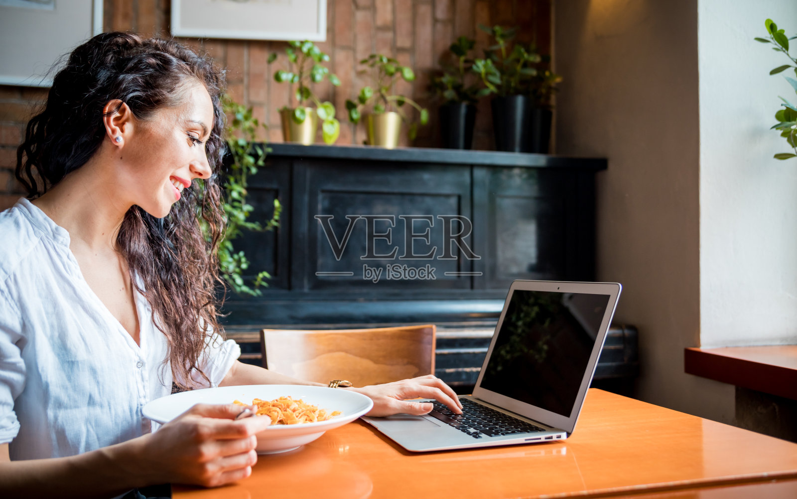 在餐厅使用笔记本电脑工作的年轻拉丁裔女性在工作期间休息照片摄影图片