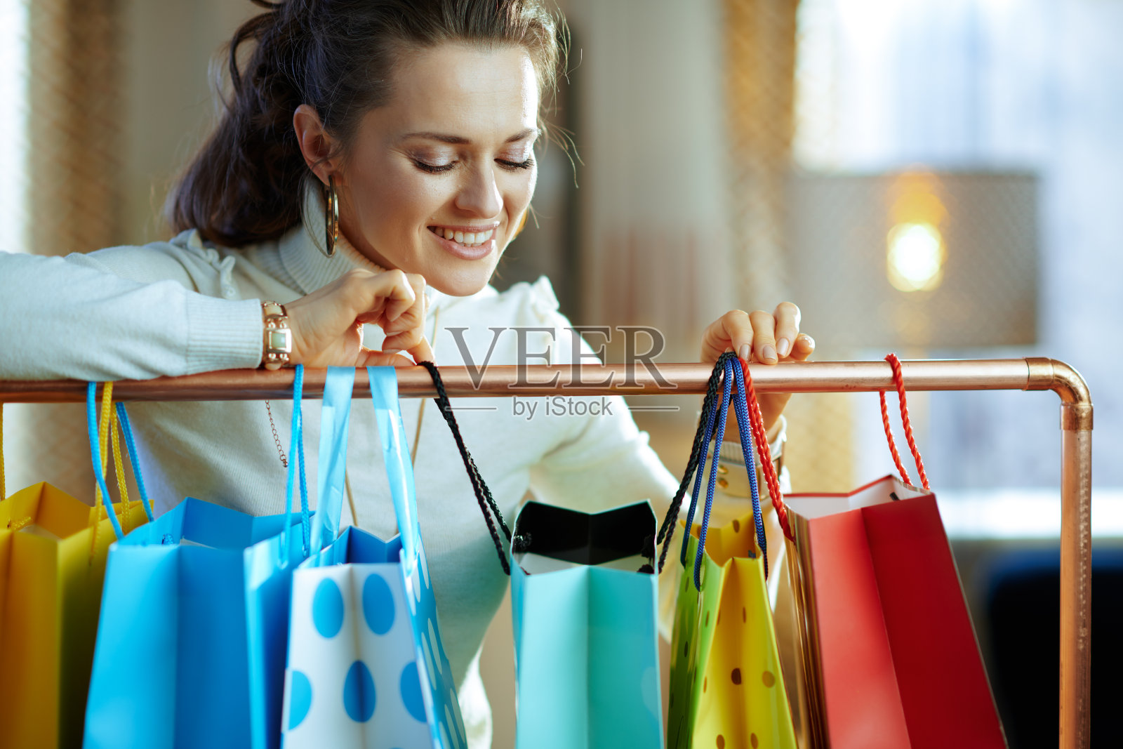 女人看着挂在铜制衣架上的购物袋照片摄影图片