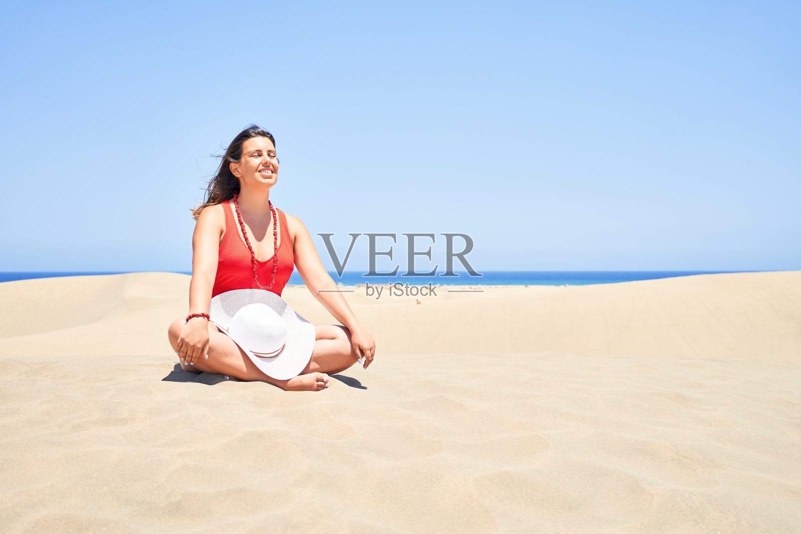 年轻美丽的女人日光浴和放松坐在沙滩上做瑜伽姿势在maspalomas沙丘bech照片摄影图片