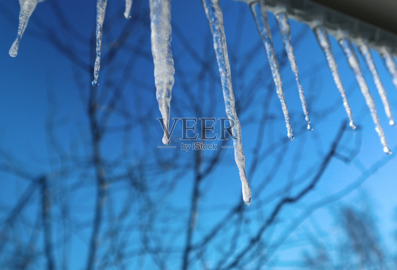 蓝色天空下的冰柱。照片摄影图片