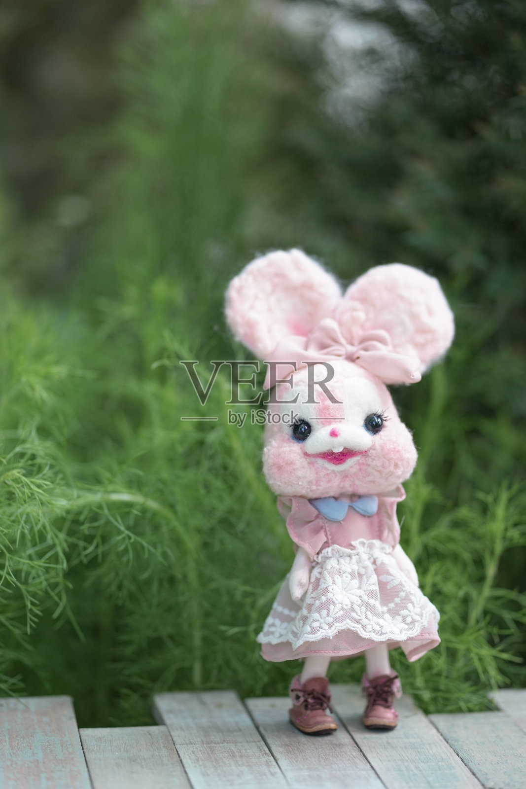 可爱的兔子玩偶。一个可爱的粉色兔子娃娃的软焦点与抽象模糊的植物和树木的背景看起来像森林。玩具摄影现在越来越流行了。照片摄影图片